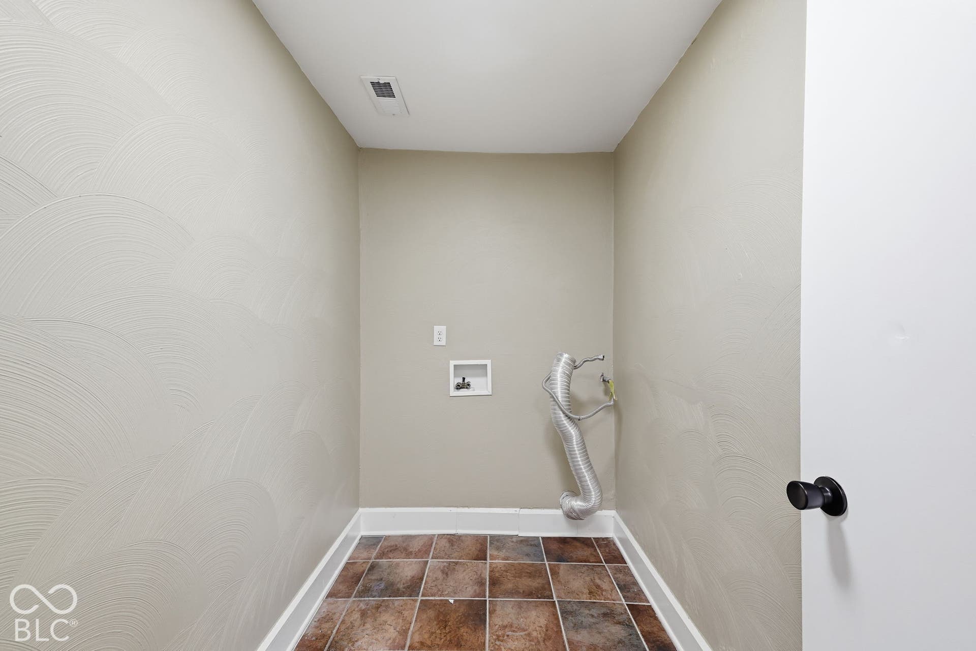 Tiled flooring, textured wall finish, and a white door with a black knob