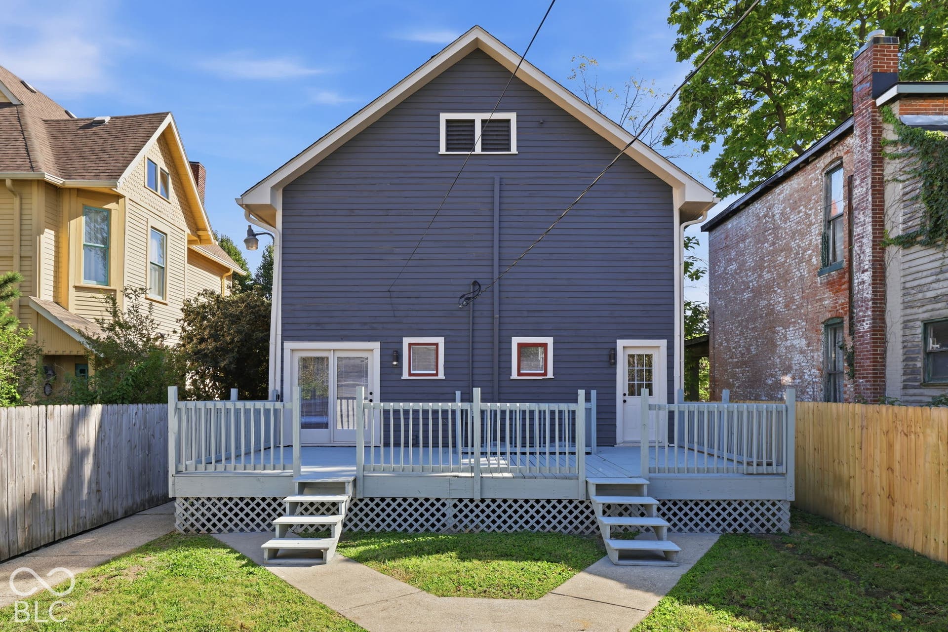 Rear facade featuring blue horizontal siding and a large light gray deck
