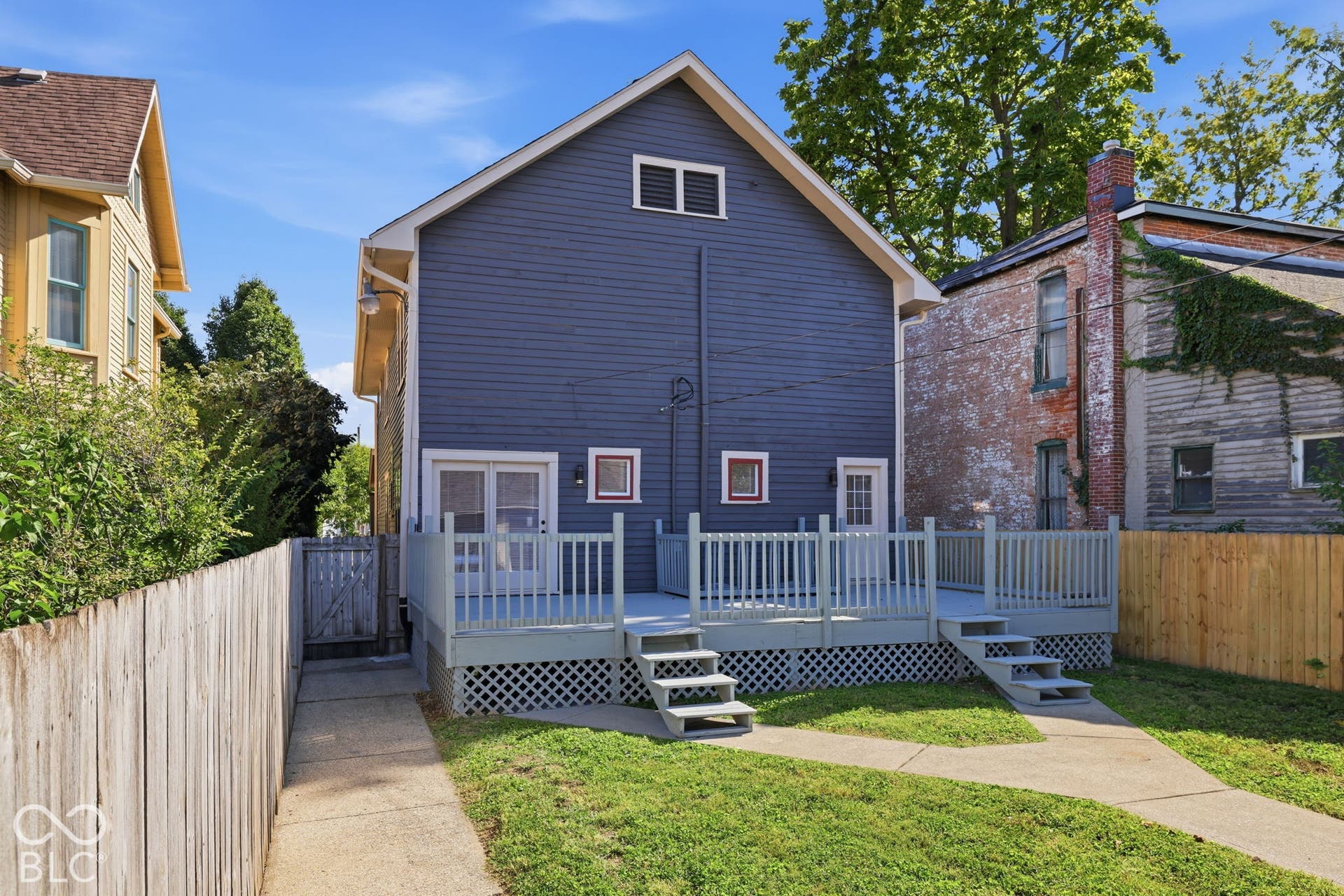 Expansive rear deck with dual stair access, featuring decorative lattice skirting and a white railing system