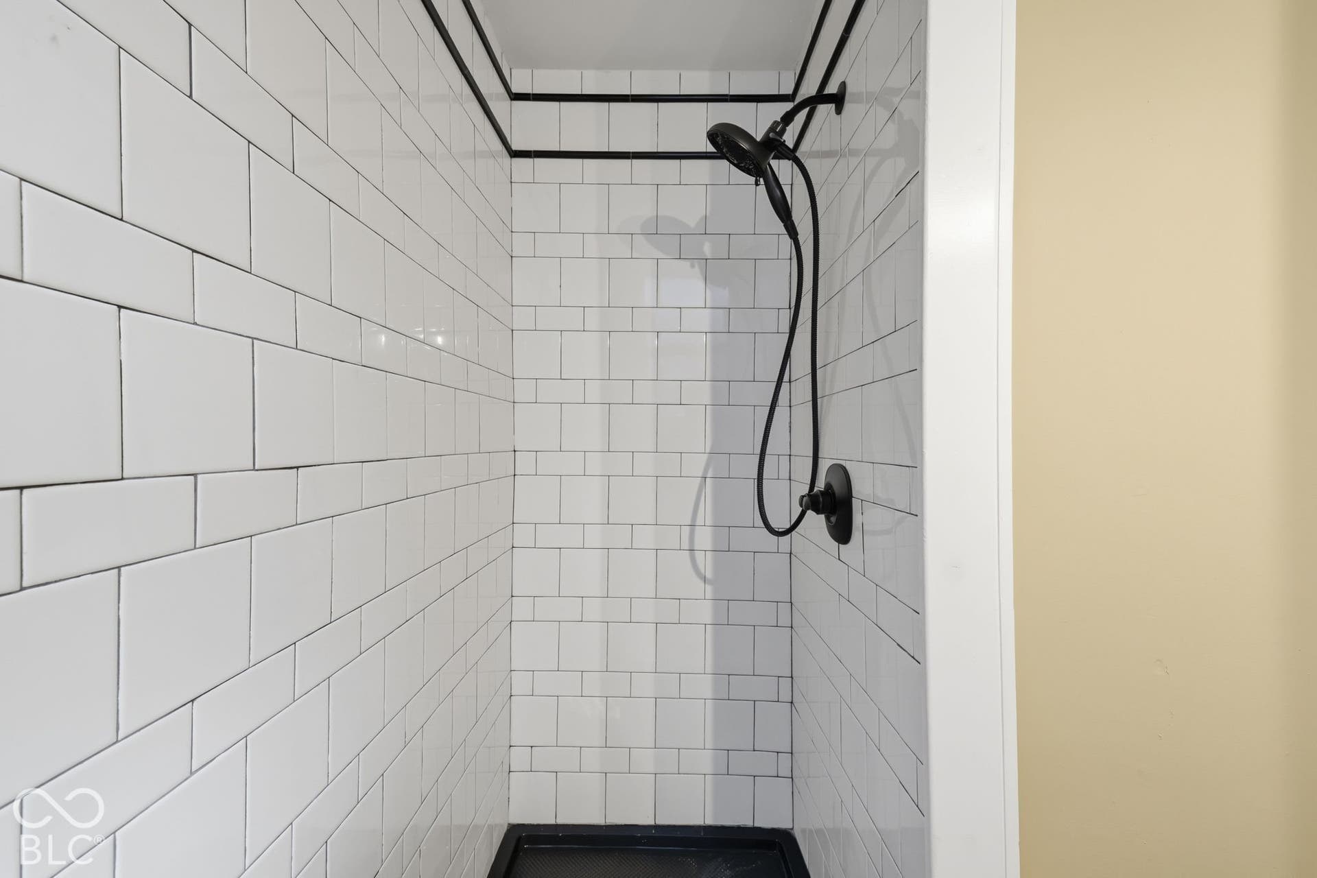 White subway tile shower enclosure with black trim