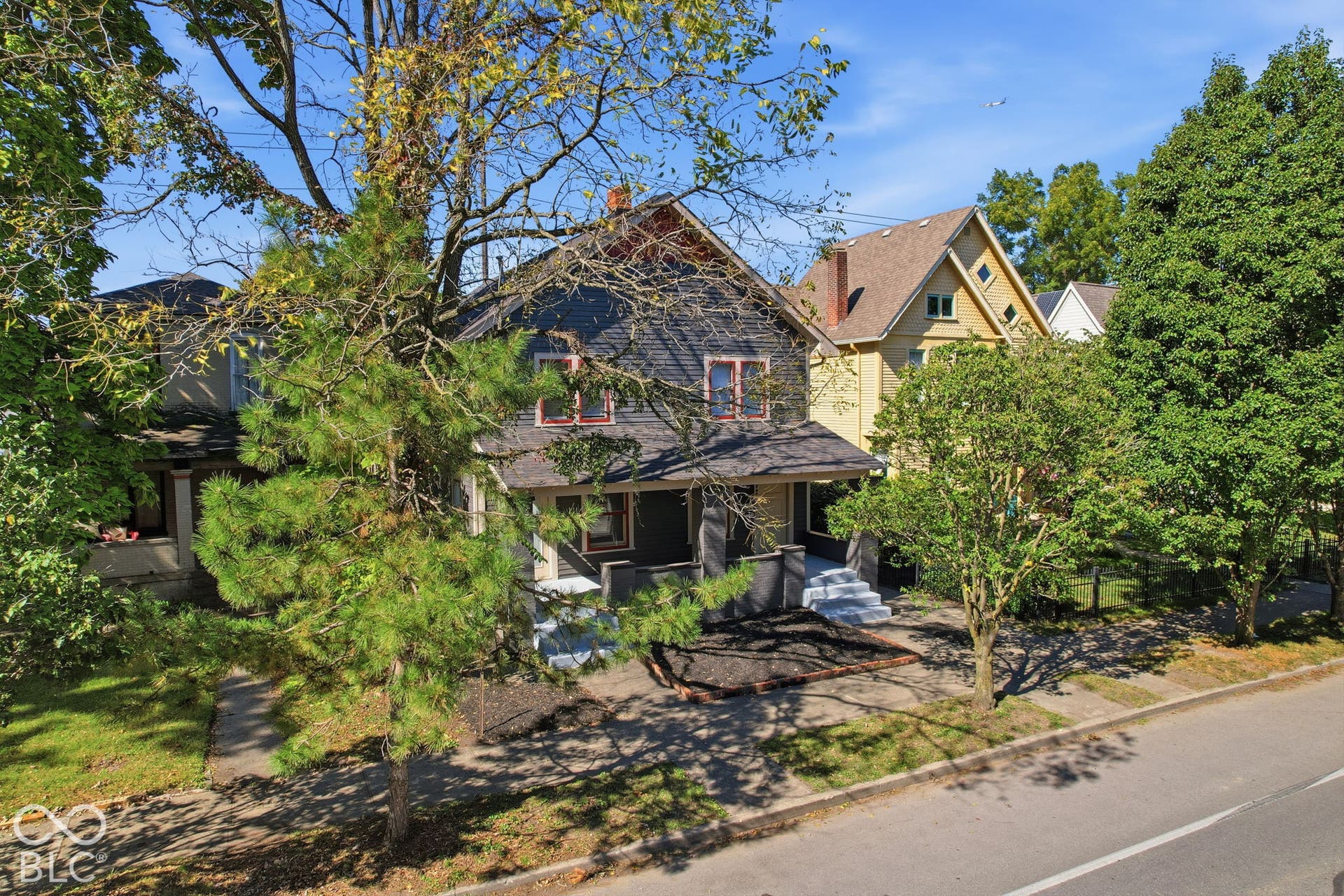 Two-story exterior with dark gray siding, a covered front porch, and red-trimmed windows