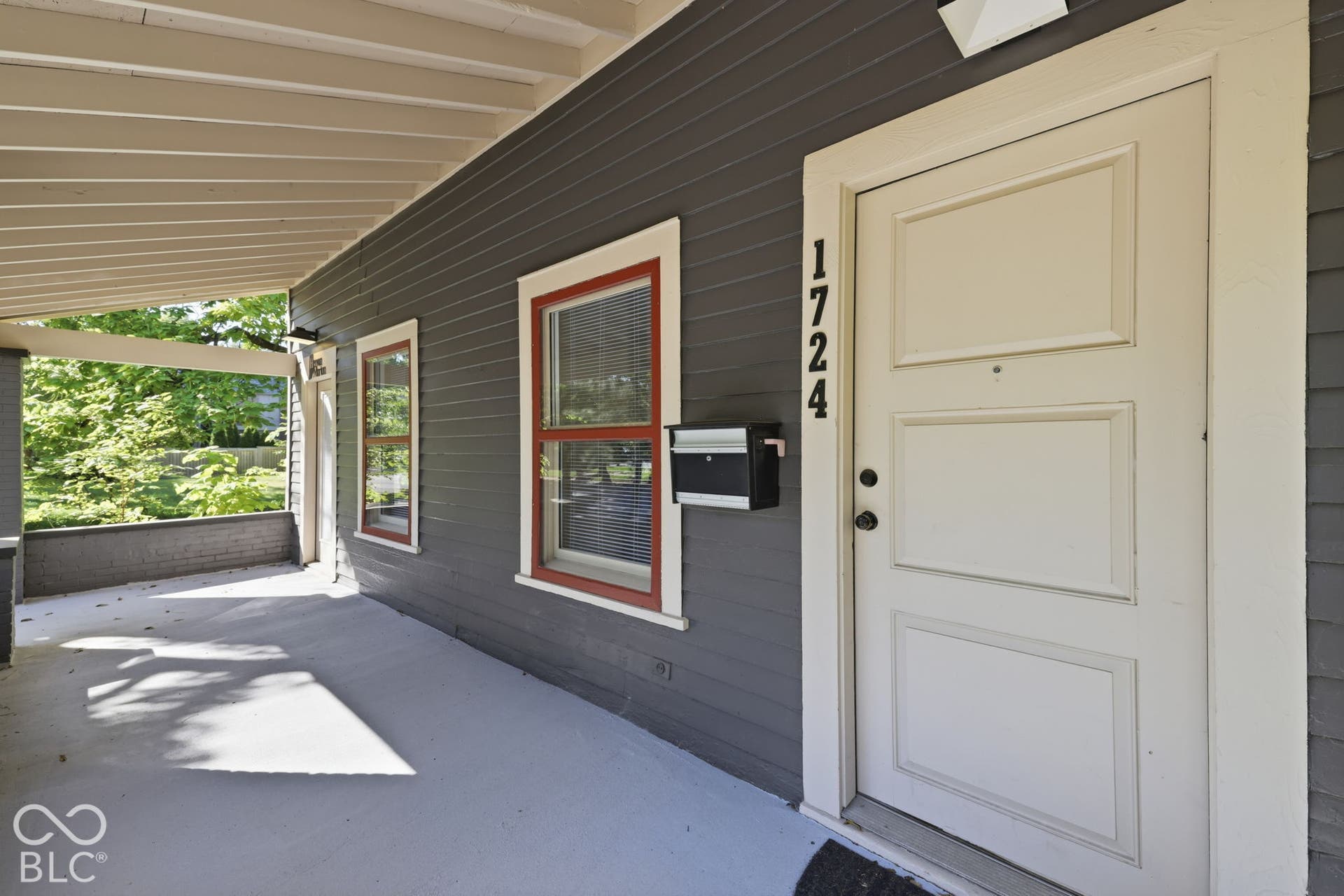 Covered front porch with painted wood siding and a paneled entry door