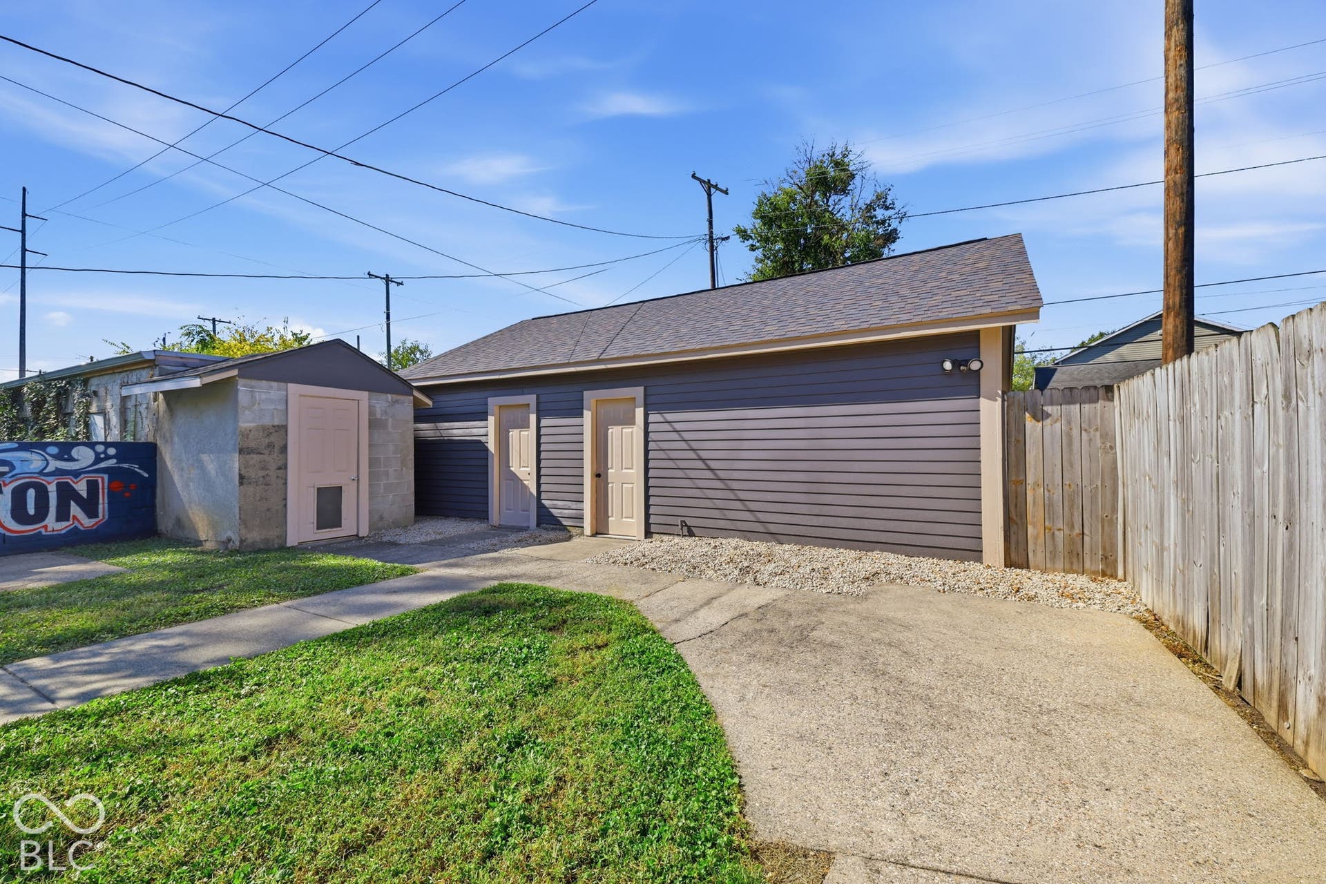 Detached garage with horizontal siding, two exterior doors, and a shingle roof