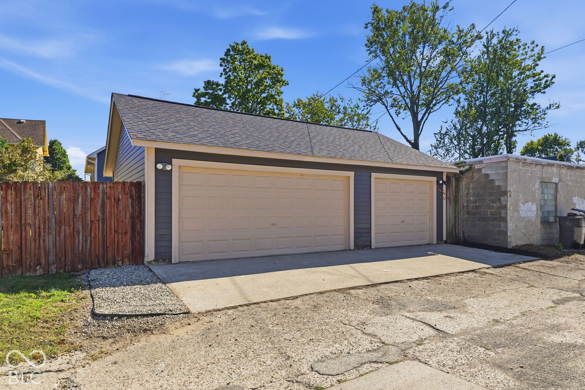 Three-car detached garage with asphalt shingle roofing and exterior lighting