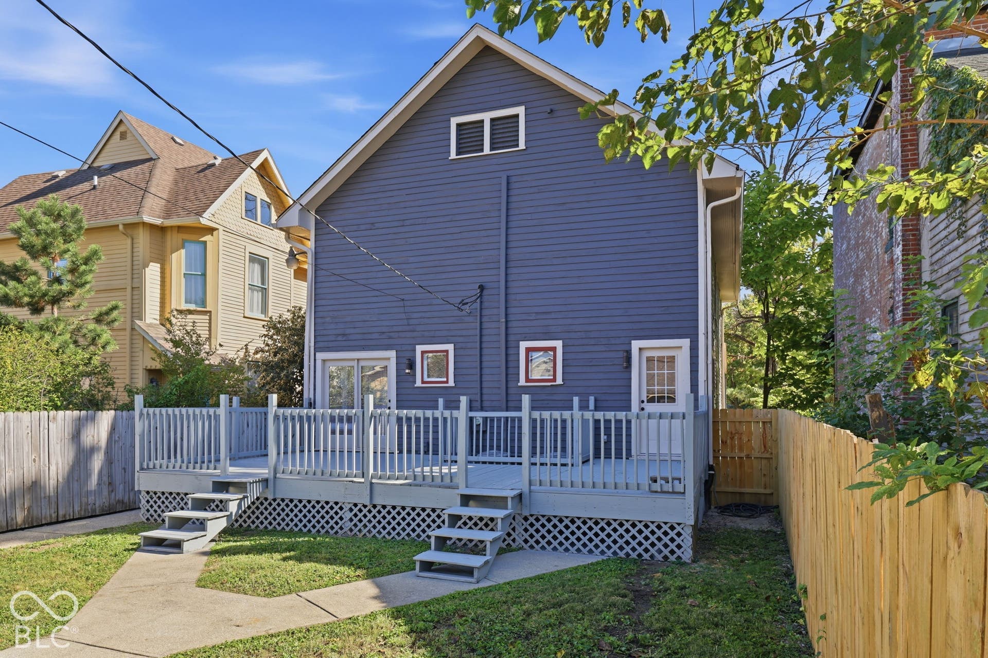 Rear exterior featuring blue siding, a multi-level deck with railings, and two sets of stairs