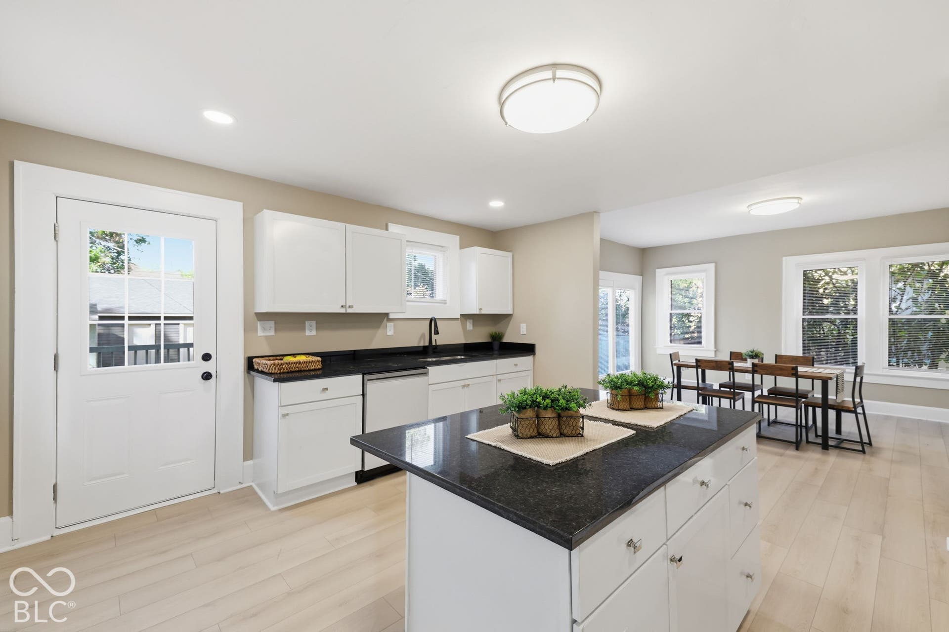 Kitchen featuring white cabinetry, dark countertops, wood-finish flooring, a central island, and multiple windows