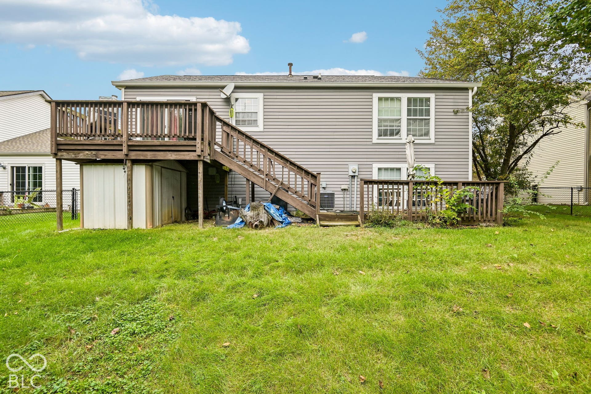 Expansive green lawn with a multi-level wood deck featuring railings