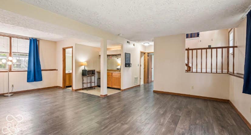 Wood-finish flooring throughout, multiple windows, built-in wet bar with wood cabinetry, and a wood railing