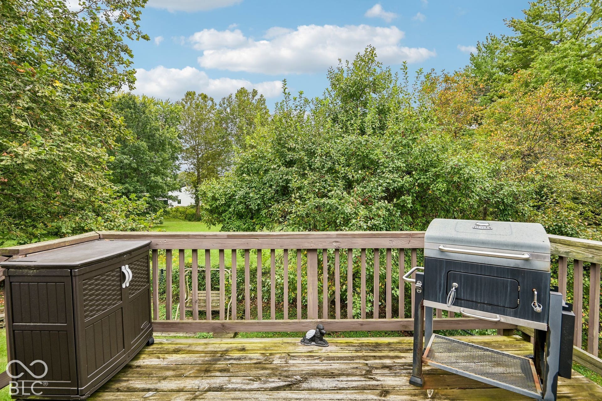 Wood-finish deck with a wood railing and mature trees