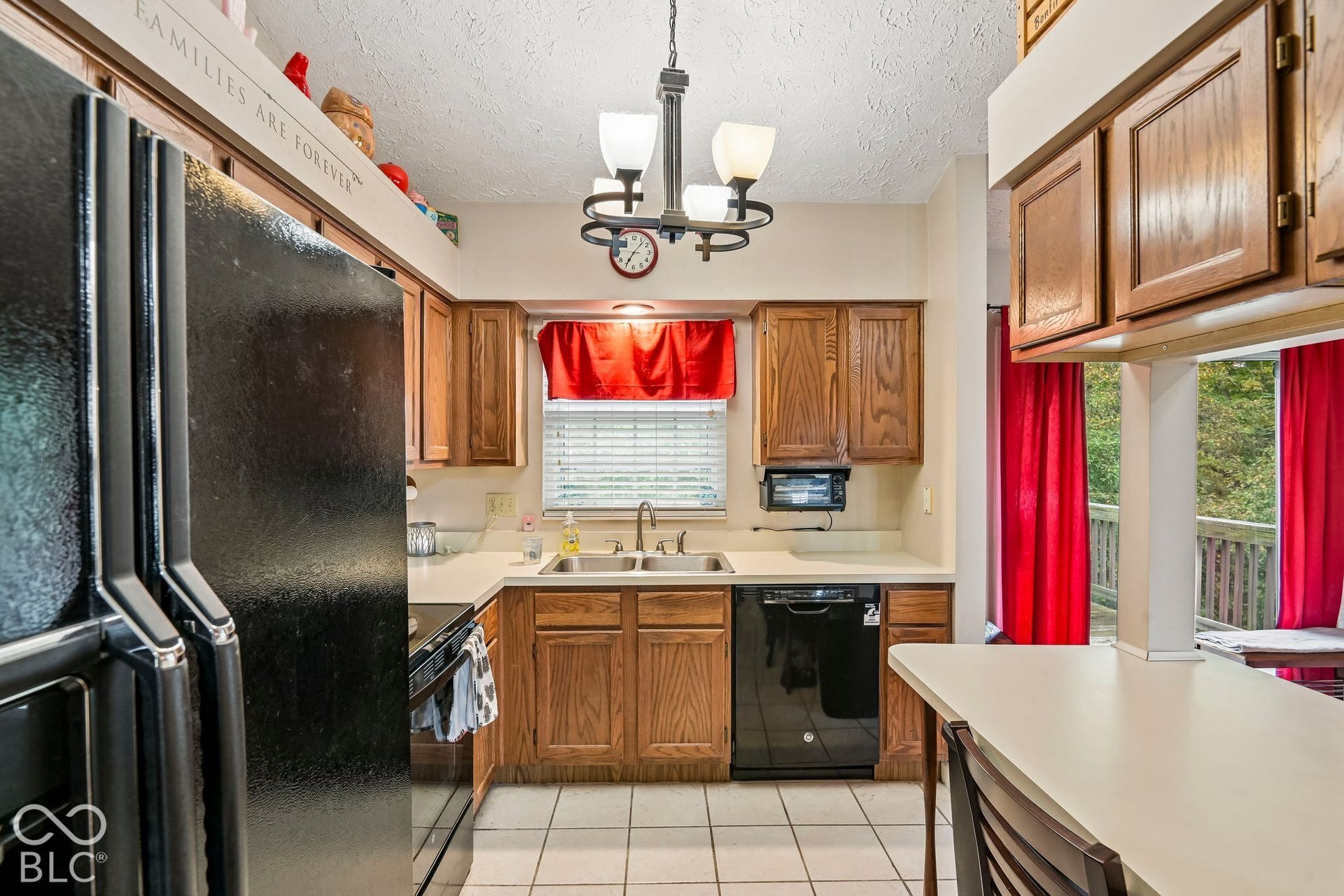 Kitchen featuring wood cabinetry, white countertops, a double basin sink, and a black dishwasher