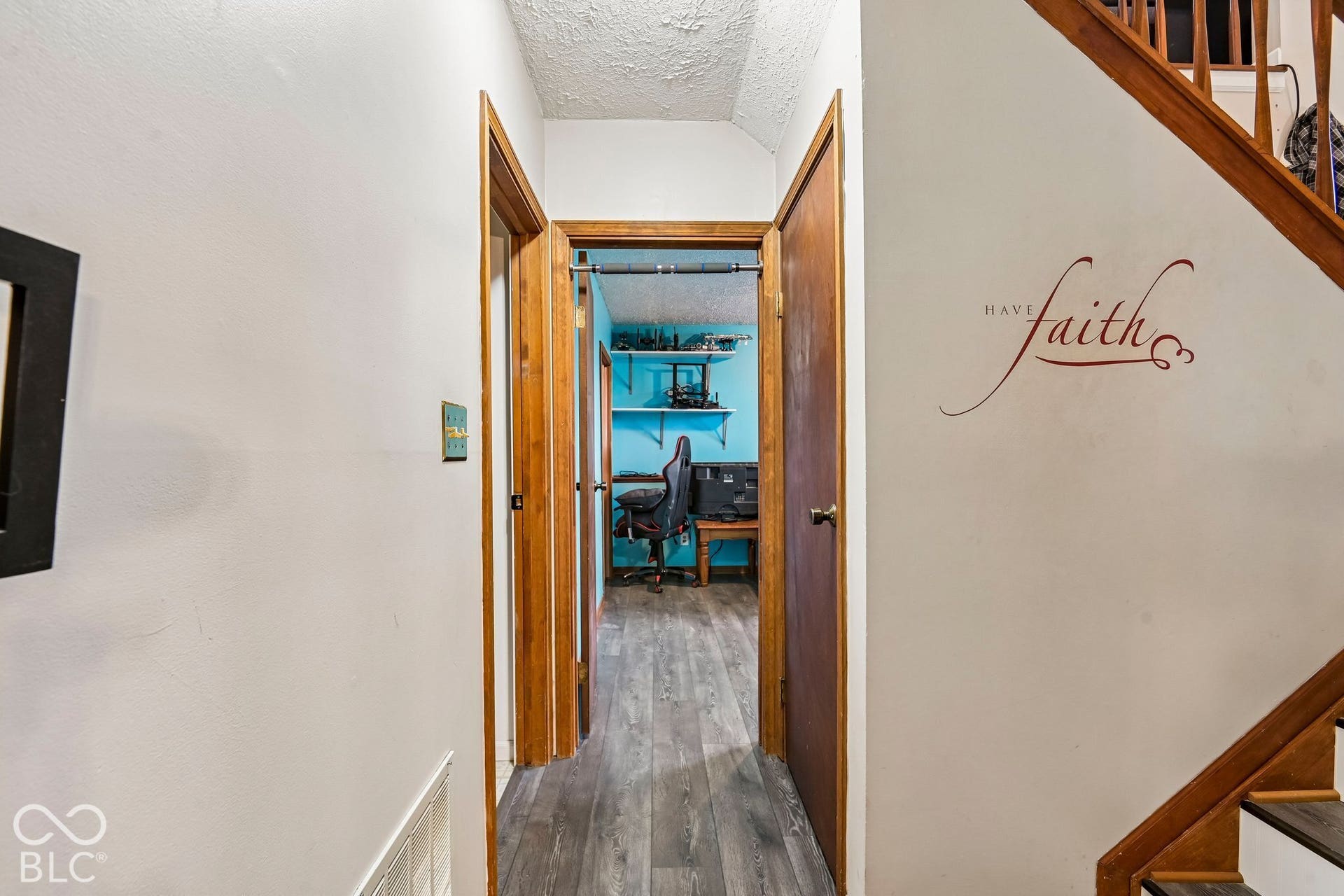 Wood-finish flooring extending into adjacent rooms, solid wood doors, and a wood staircase with risers