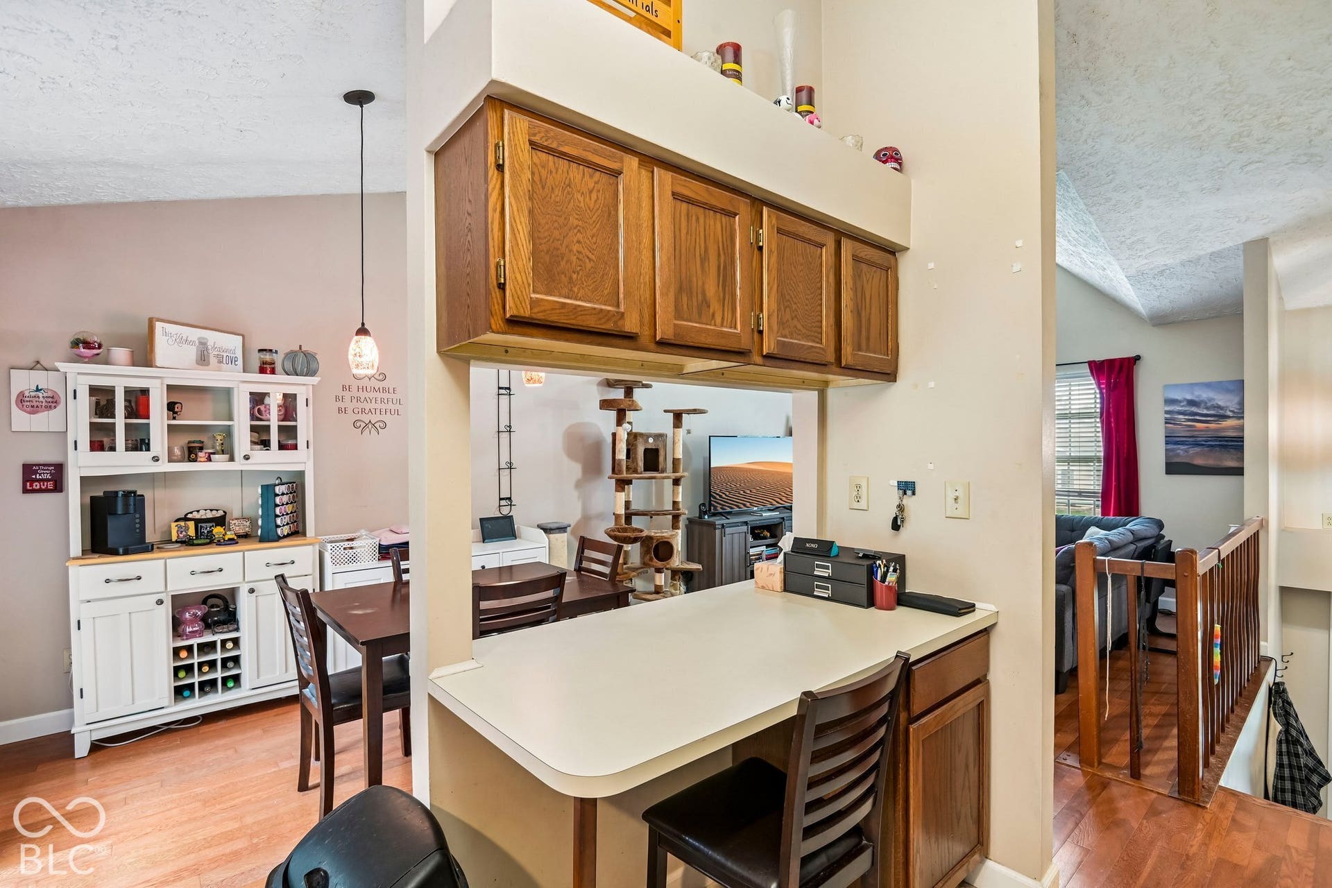 Wood-finish flooring, built-in cabinetry, counter space, and an overhead pendant light