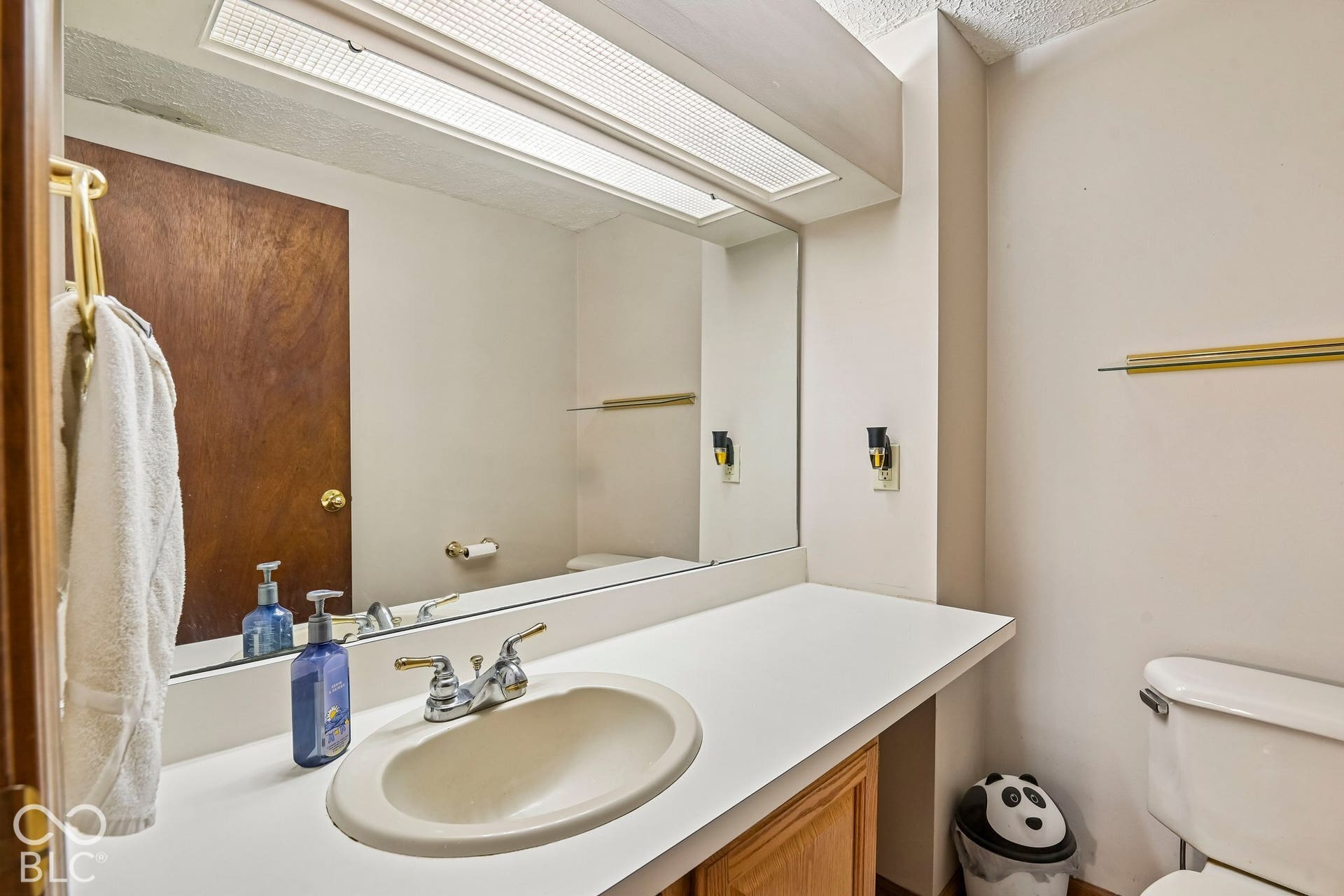 Built-in vanity with an integrated sink, laminate countertop, and wood-finish cabinetry