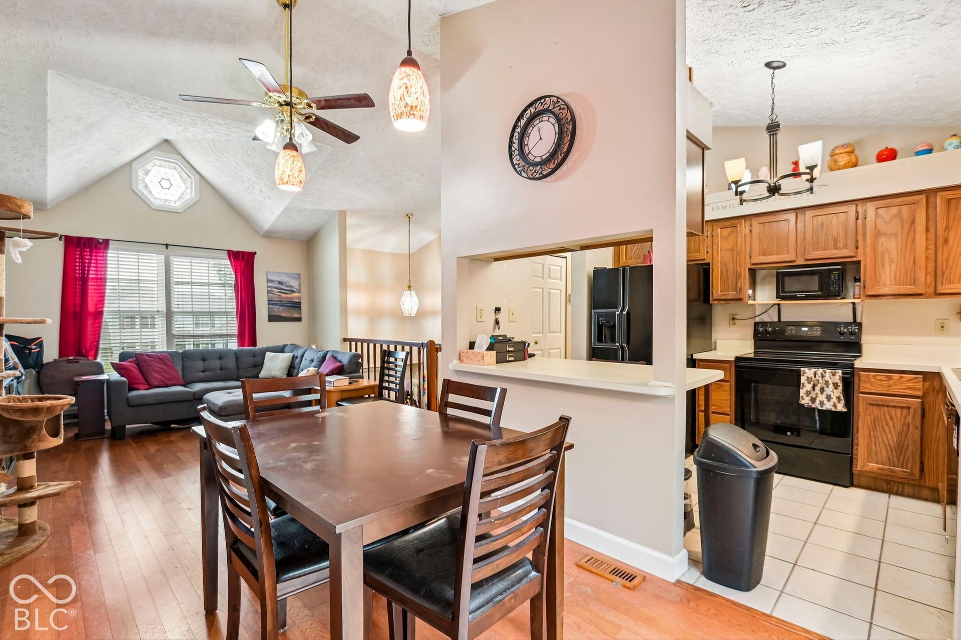 Open-concept living area featuring a vaulted ceiling, wood-finish flooring, and a kitchen with wood cabinetry