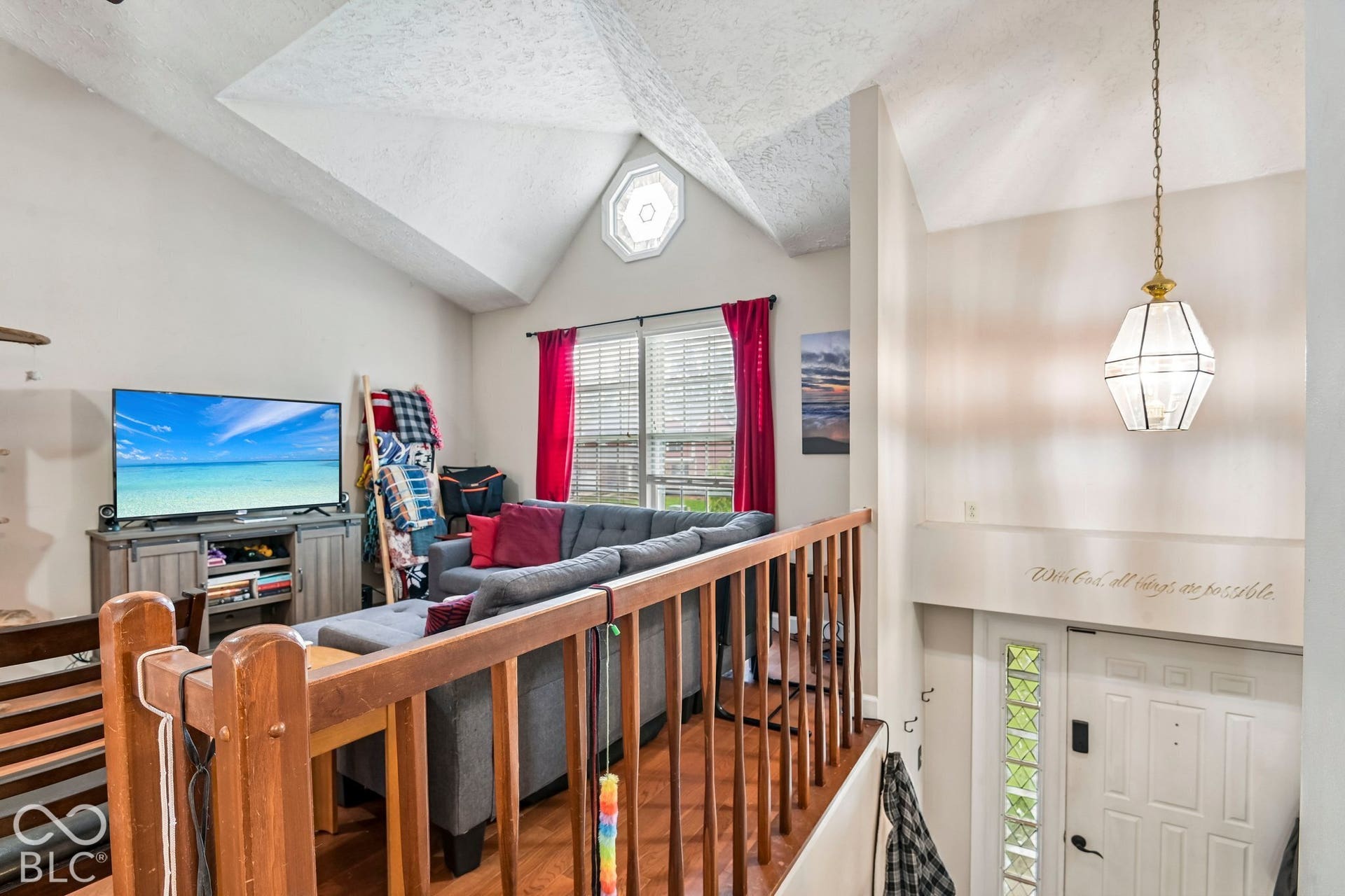 Vaulted ceilings, wood-finish flooring, octagonal window, white paneled entry door, and glass block sidelights