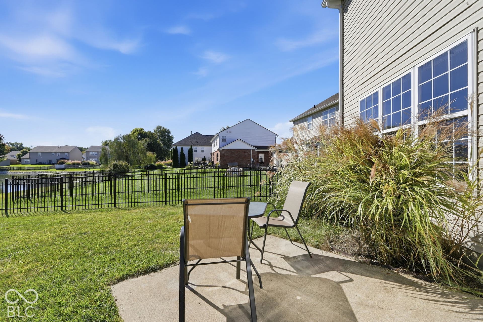 8035 Meadow Bend Lane, Indianapolis, IN 46259 Concrete patio with established landscaping, overlooking a fenced yard and water feature