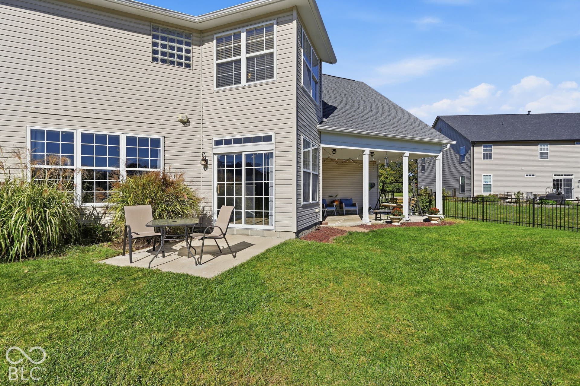 8035 Meadow Bend Lane, Indianapolis, IN 46259 Rear exterior featuring a covered patio, an additional concrete patio, sliding glass doors, and a partial black metal fence