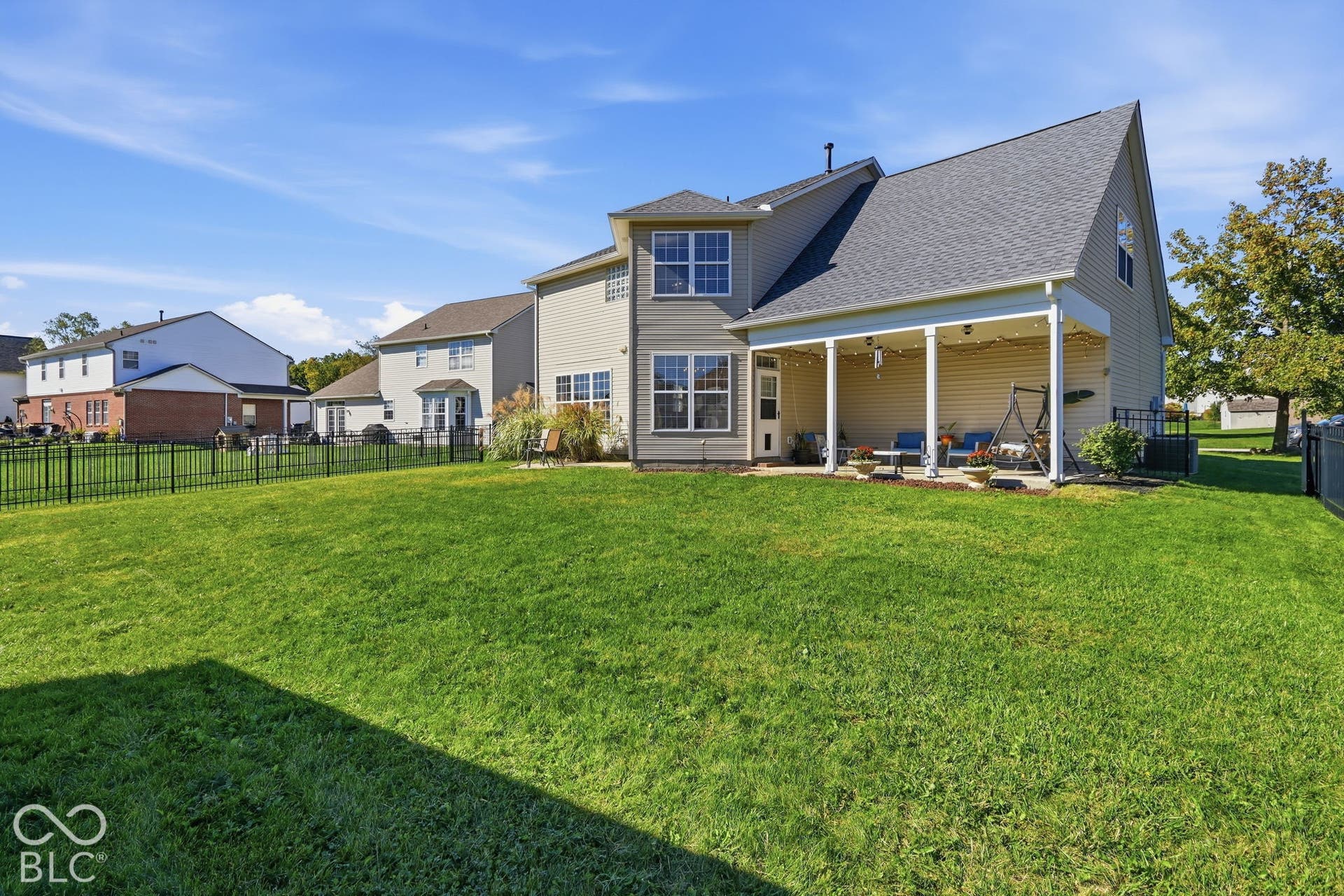 8035 Meadow Bend Lane, Indianapolis, IN 46259 Expansive green lawn with a covered patio featuring multiple pillars and outdoor lighting