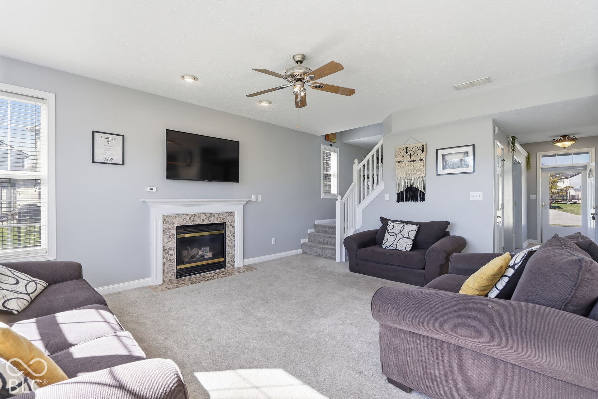 8035 Meadow Bend Lane, Indianapolis, IN 46259 Living area featuring a fireplace with a stone surround, a ceiling fan, recessed lighting, and a staircase with white railings
