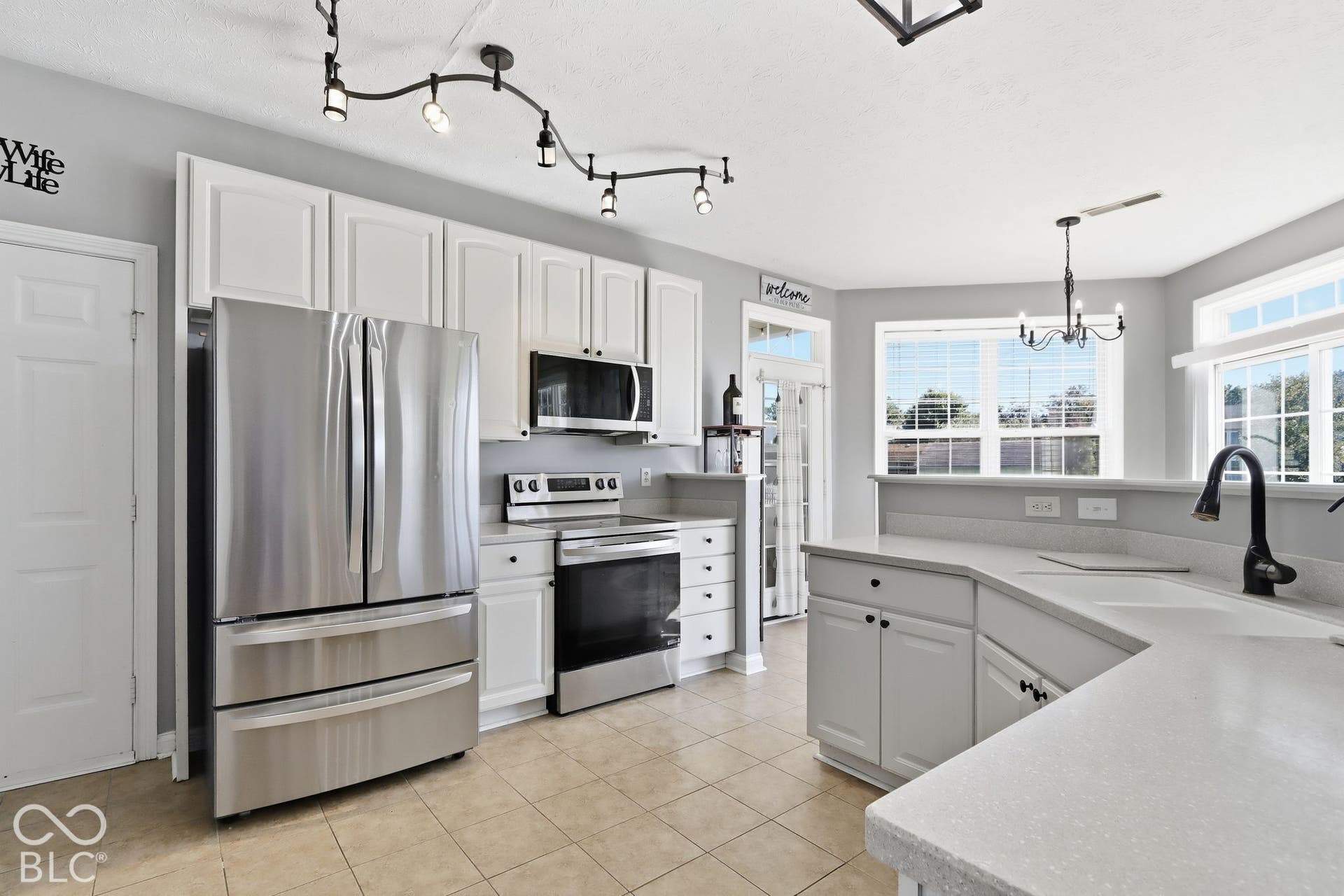 8035 Meadow Bend Lane, Indianapolis, IN 46259 White cabinetry, stainless steel appliances, light-toned countertops, ceramic tile flooring, and track lighting