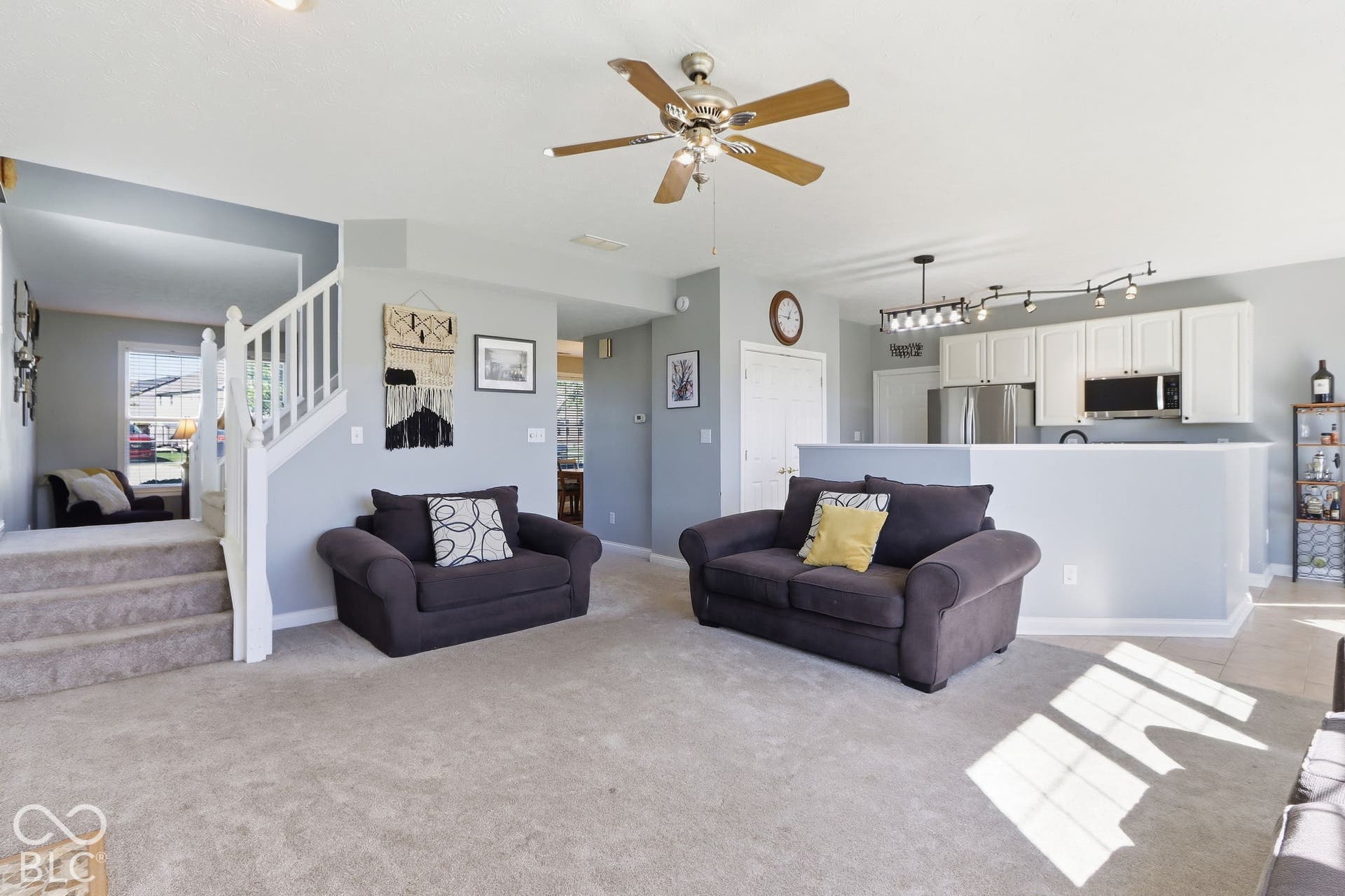 8035 Meadow Bend Lane, Indianapolis, IN 46259 Open-concept living area featuring a ceiling fan, carpeted flooring, and a stairway with white balusters
