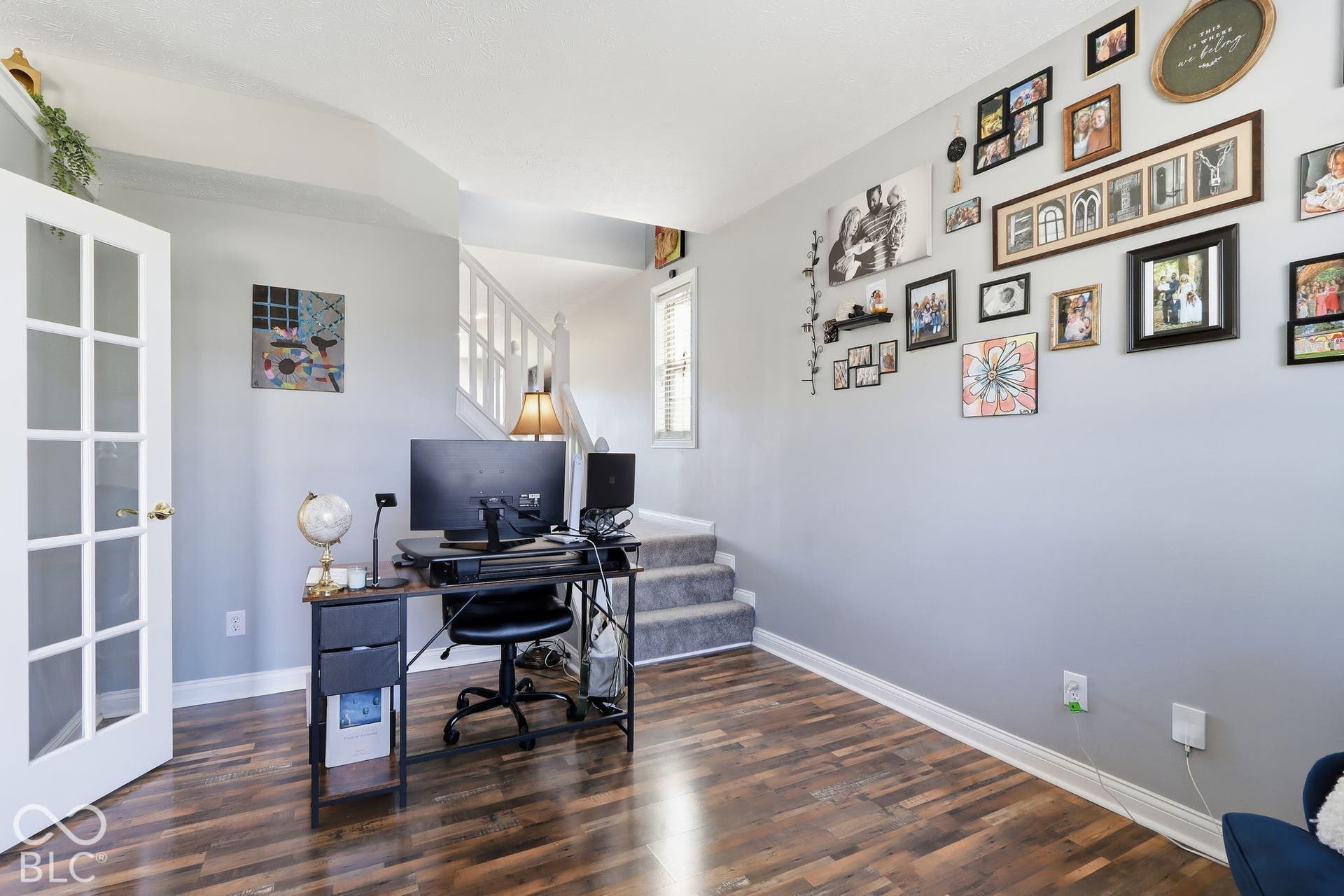 8035 Meadow Bend Lane, Indianapolis, IN 46259 Wood-finish flooring, white French doors, light gray wall color, white staircase balusters, and a window with white trim