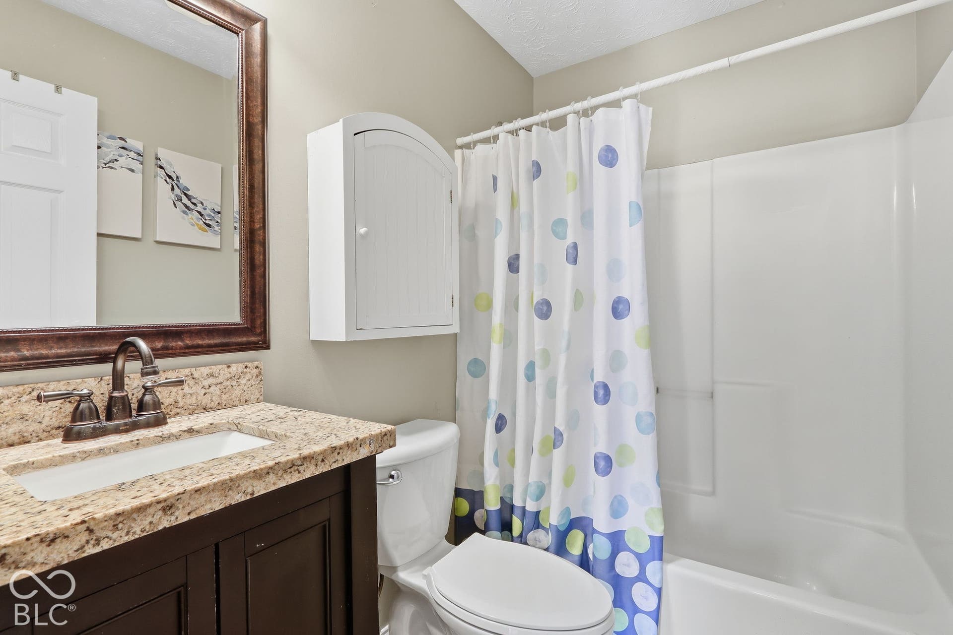 8035 Meadow Bend Lane, Indianapolis, IN 46259 Bathroom with a built-in shower/tub combination, vanity with an integrated sink, brown wood-finish cabinetry, and a framed wall mirror