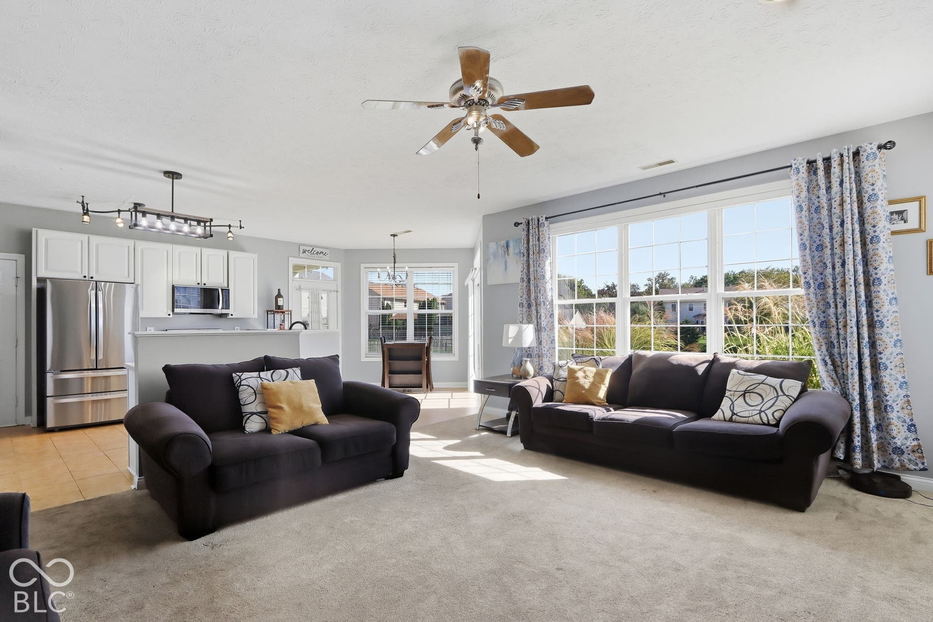 8035 Meadow Bend Lane, Indianapolis, IN 46259 Open-concept living area with large windows, light gray walls, and a ceiling fan