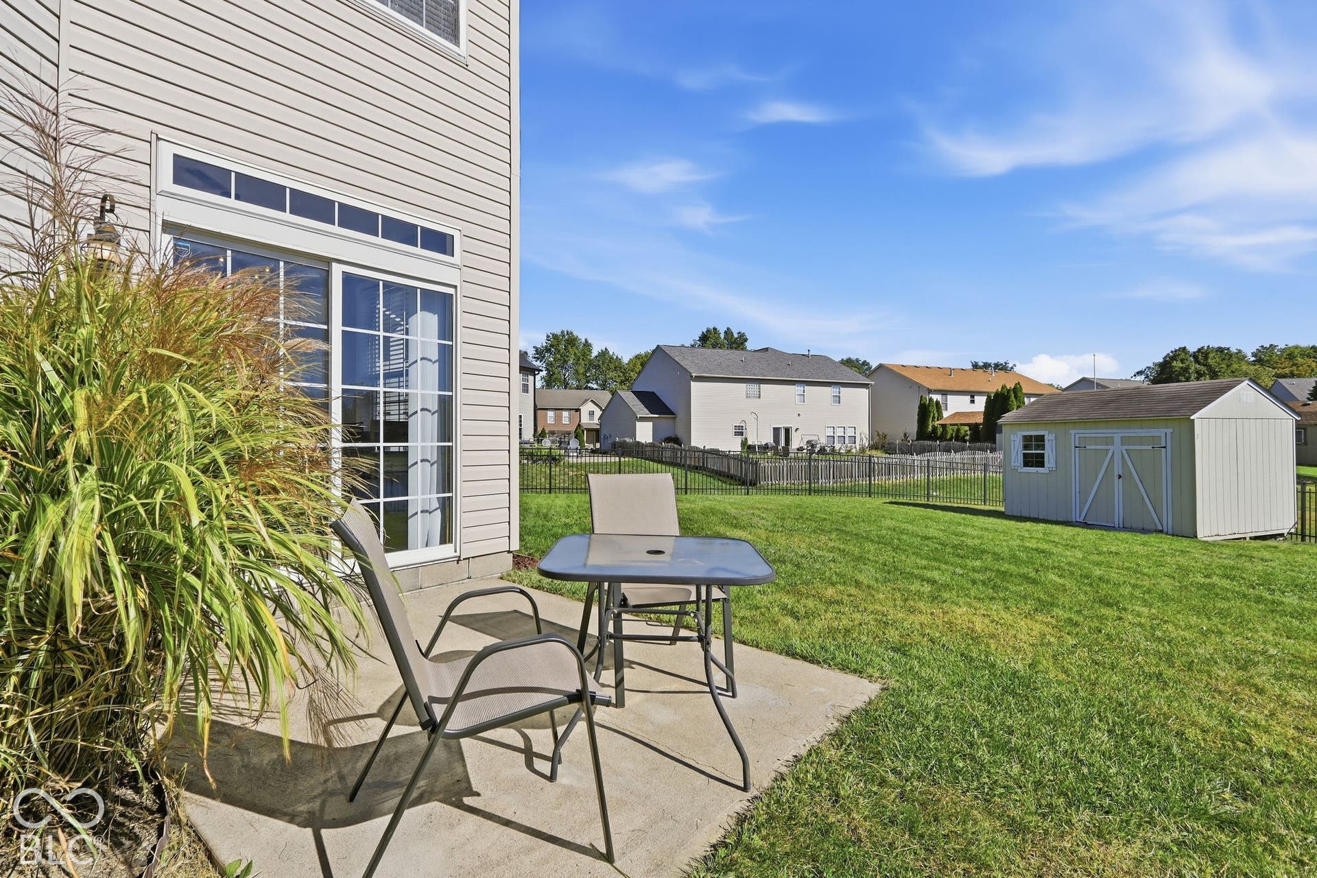 8035 Meadow Bend Lane, Indianapolis, IN 46259 Slider door access to a concrete patio, expansive grassed yard, and a detached storage shed