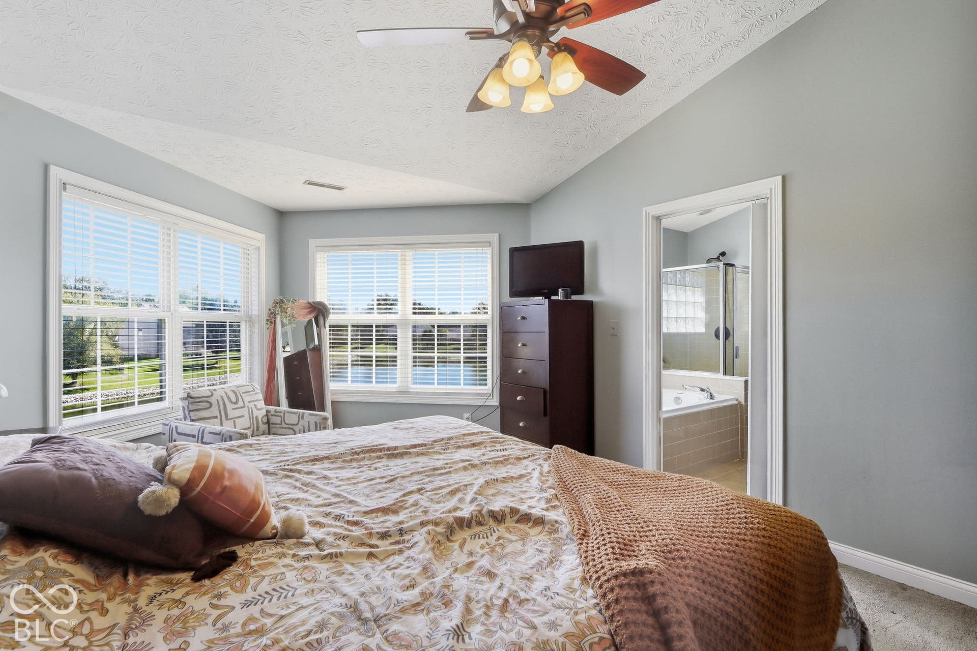 8035 Meadow Bend Lane, Indianapolis, IN 46259 Primary Bedroom. Vaulted ceiling with a ceiling fan, multiple windows with blinds, and an attached bathroom featuring a shower and built-in tub