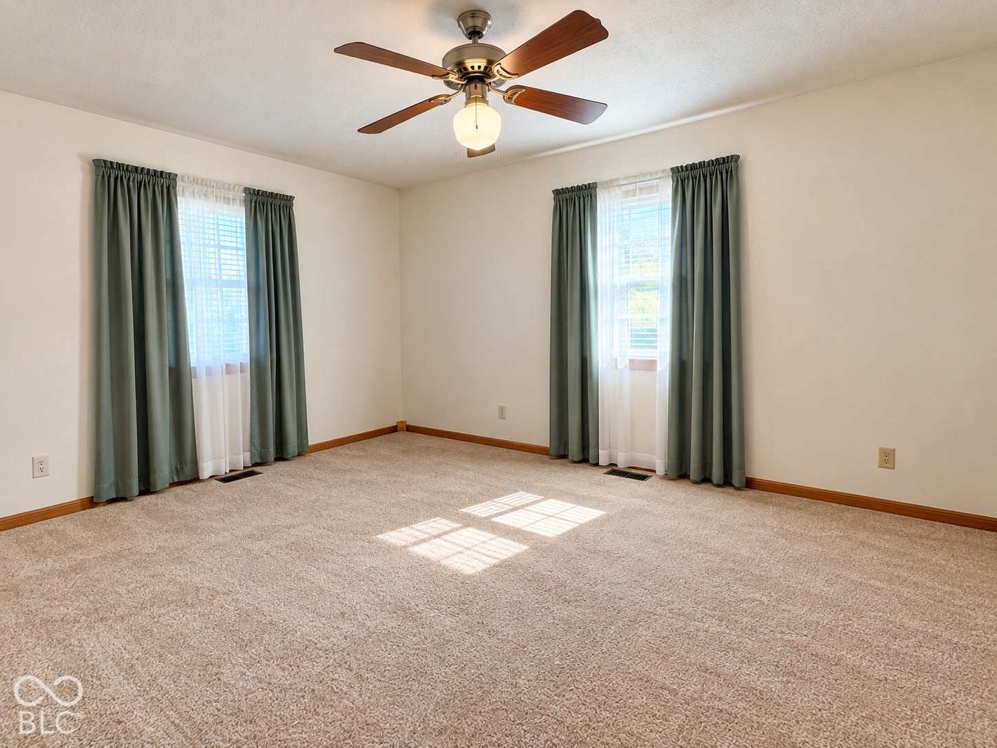 Carpeted flooring, two windows with blinds, ceiling fan with integrated lighting, and neutral wall paint