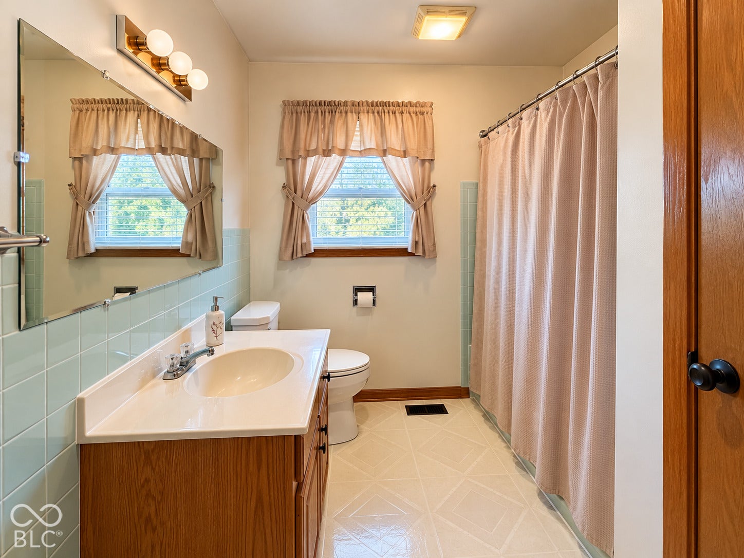 Bathroom featuring a wood-finish vanity with an integrated sink, a large wall-mounted mirror, and tile flooring