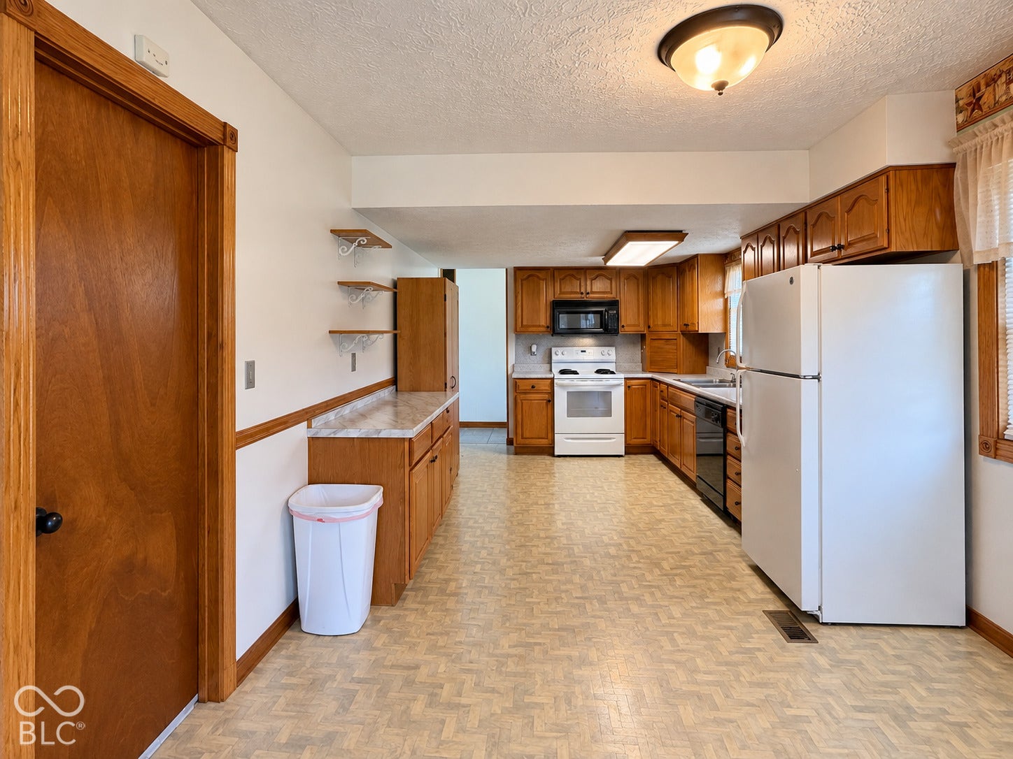Kitchen featuring wood-finish cabinetry, white appliances, and a built-in microwave