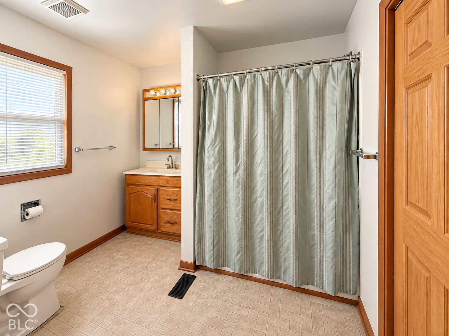 Bathroom featuring a wood-finish vanity with a built-in sink, medicine cabinet with mirrored doors, and overhead vanity lighting