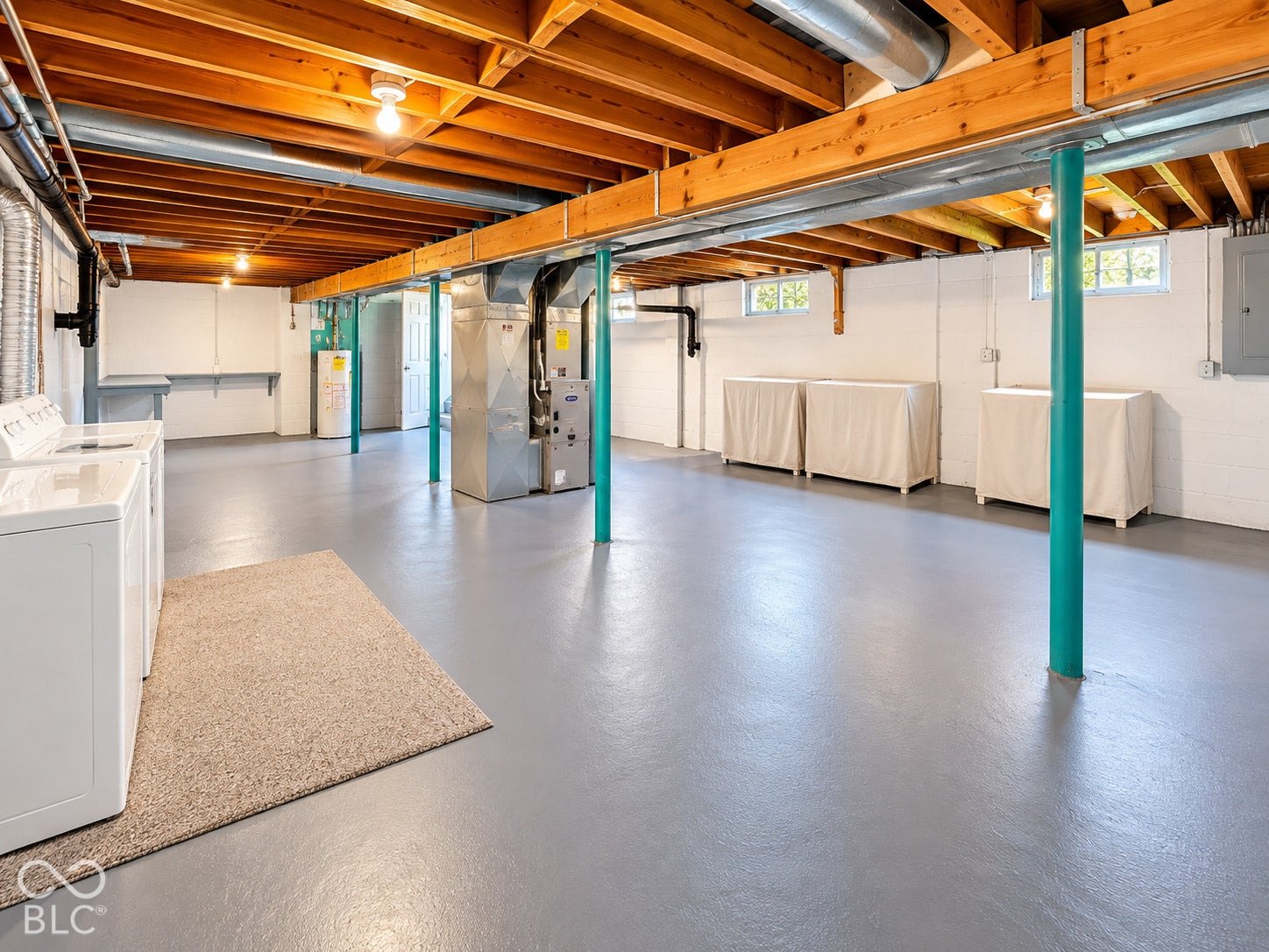 Spacious lower level featuring exposed wood beam ceiling, painted concrete flooring, and multiple windows