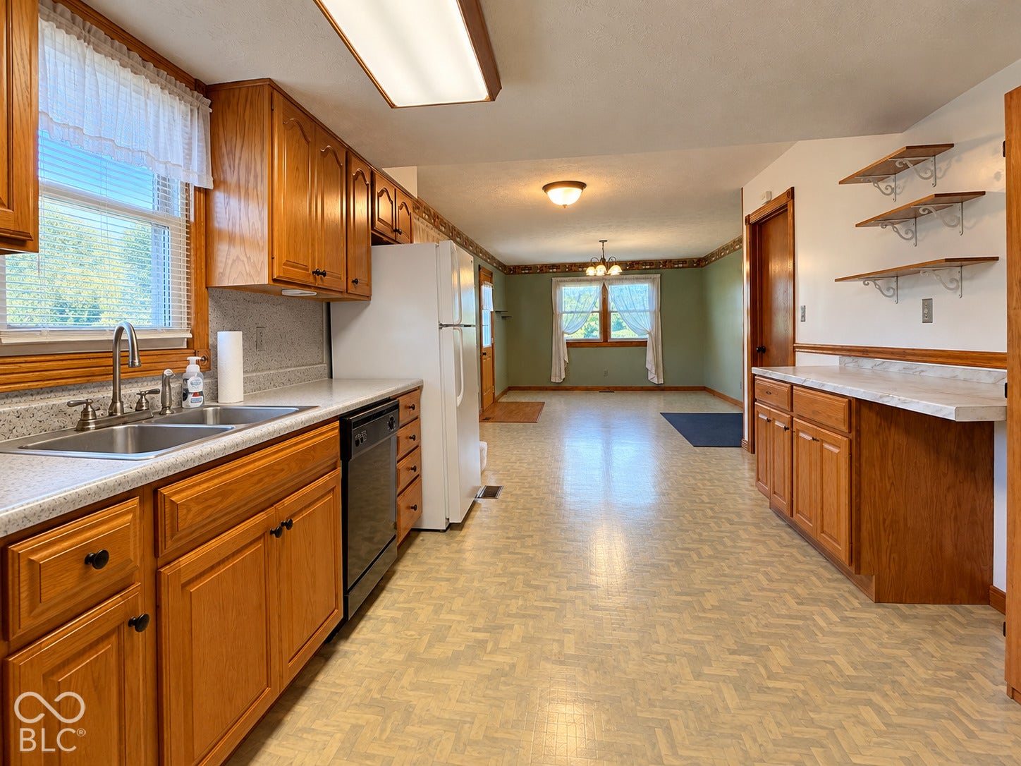 Kitchen featuring wood-finish cabinetry, a double basin sink with a chrome faucet, a built-in dishwasher, and patterned flooring