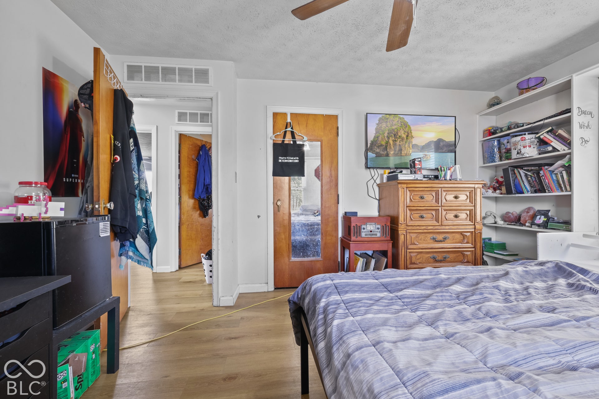 Wood-finish flooring with white walls, built-in shelving, and a ceiling fan