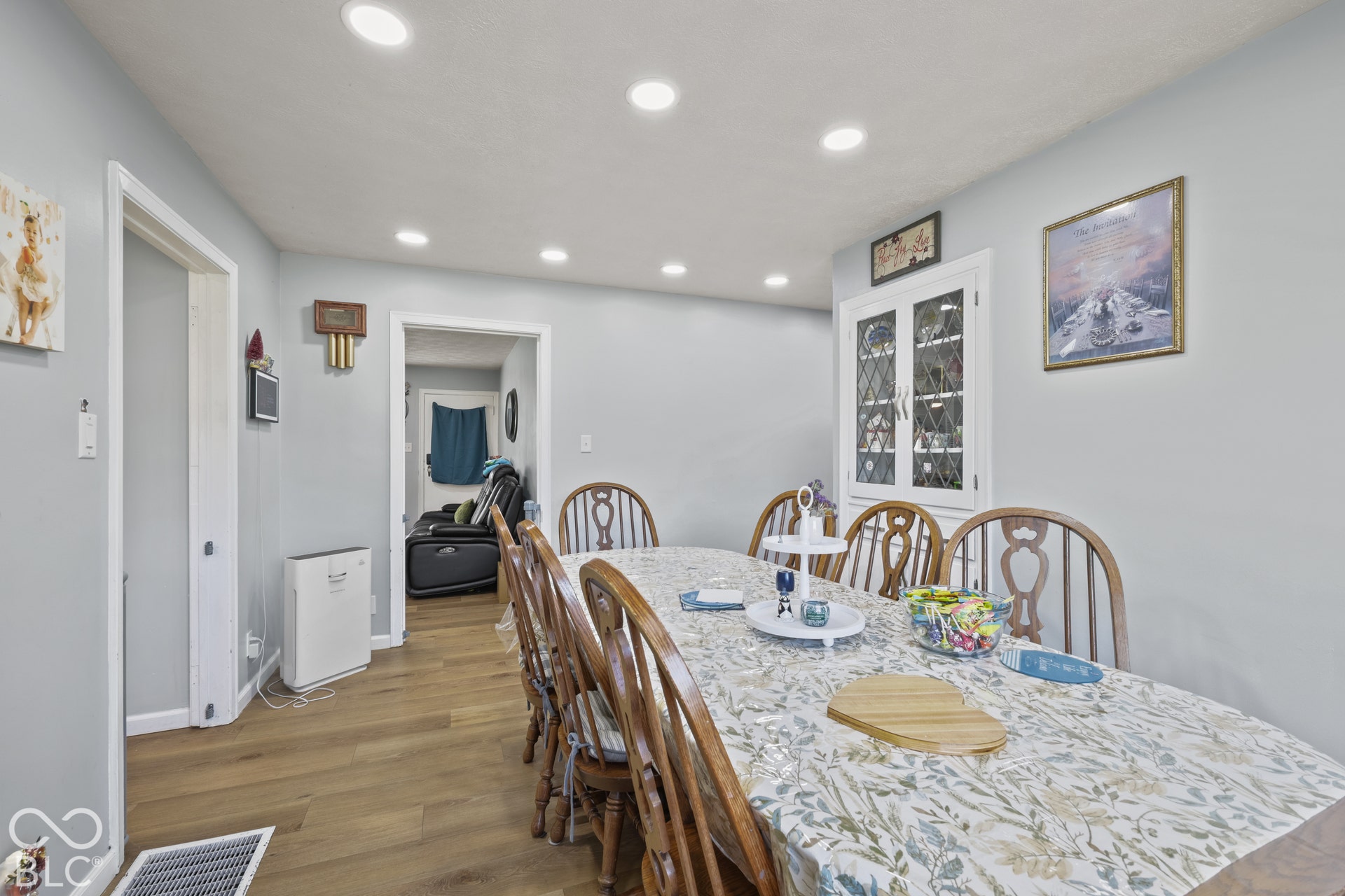 Recessed lighting, wood-finish flooring, white built-in cabinetry with glass paneled doors, and painted walls