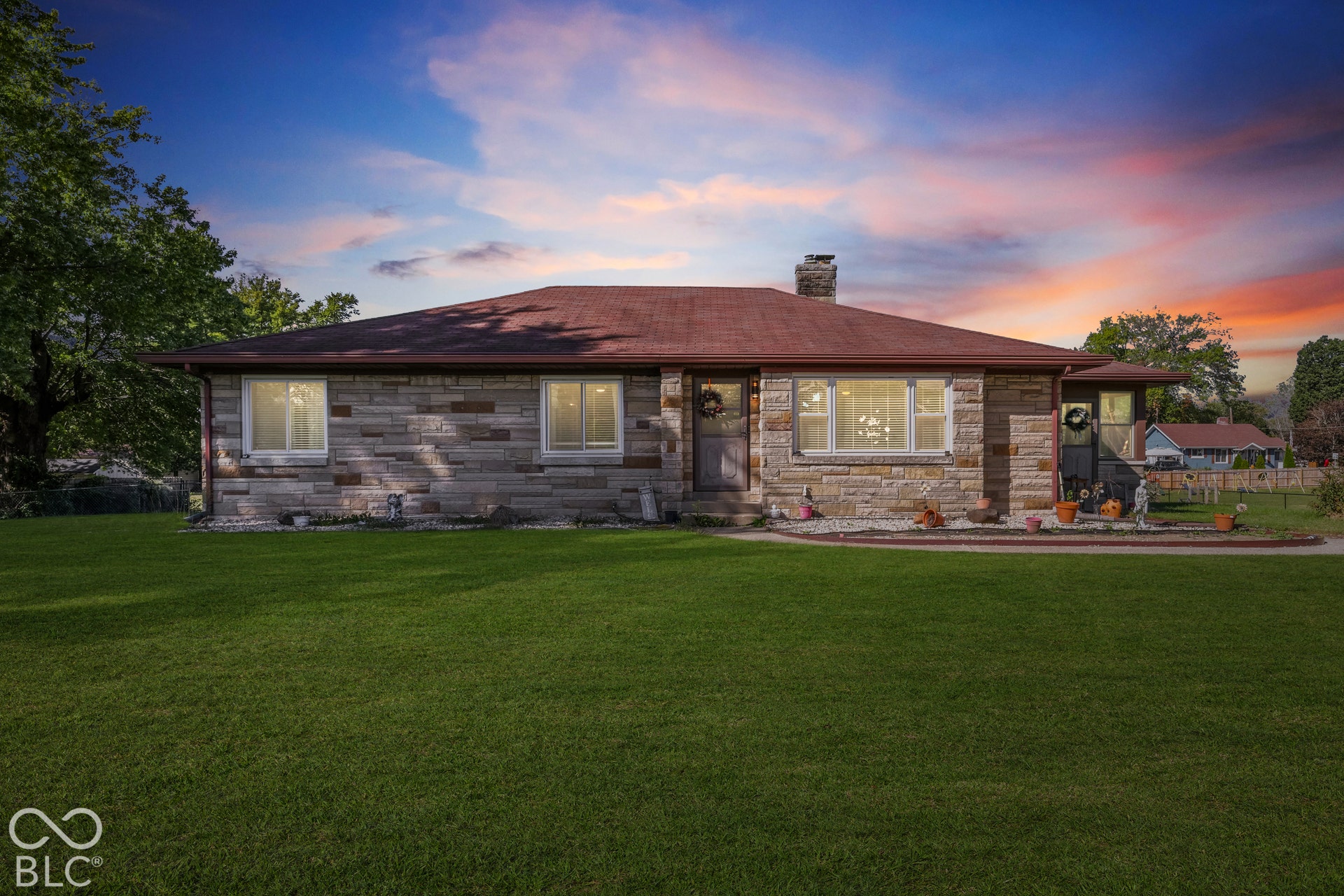 Stone veneer exterior with a red shingle roof, featuring a prominent chimney and a well-maintained front lawn