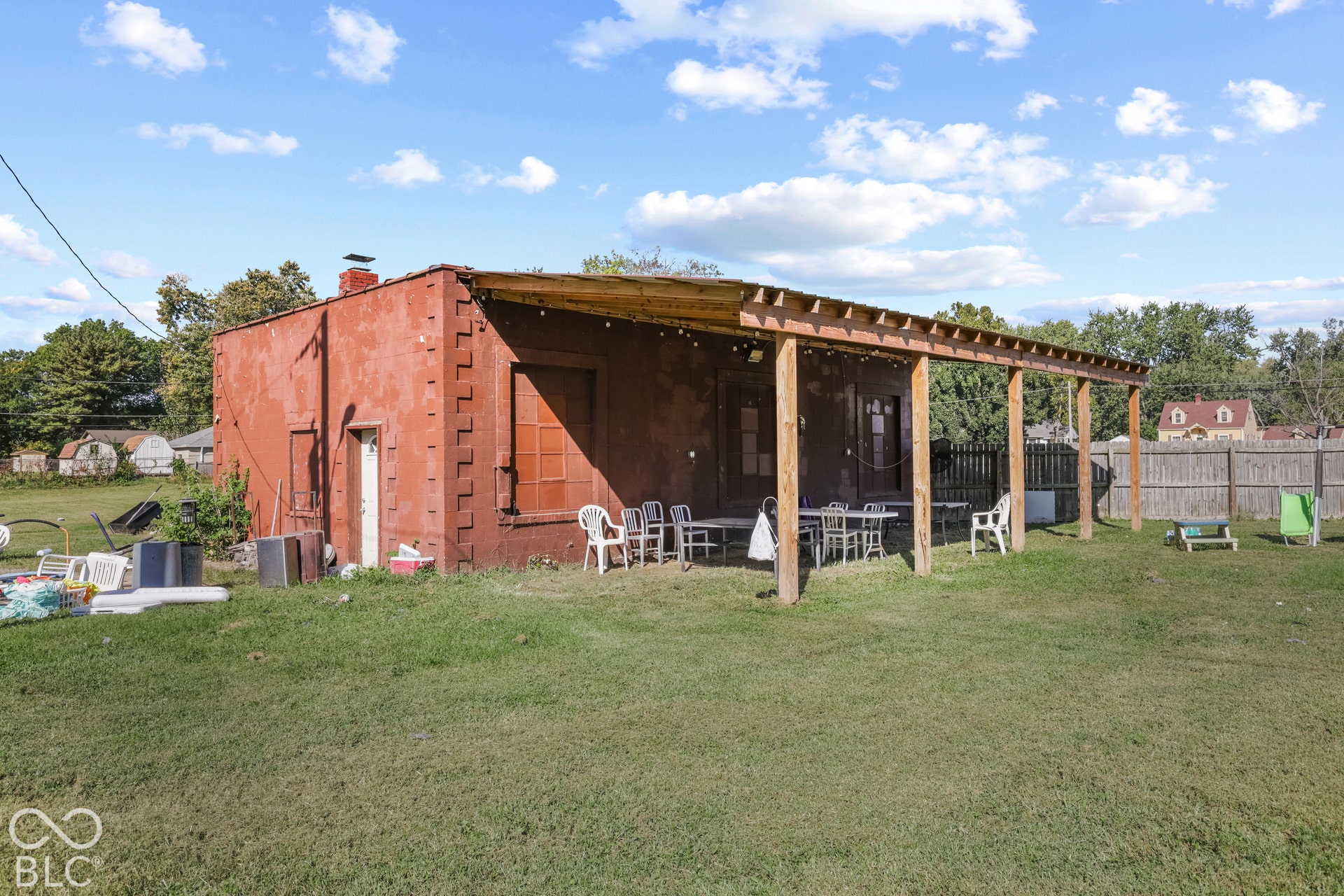 Red stucco exterior with decorative brickwork, wood-framed pergola, and a grassy yard