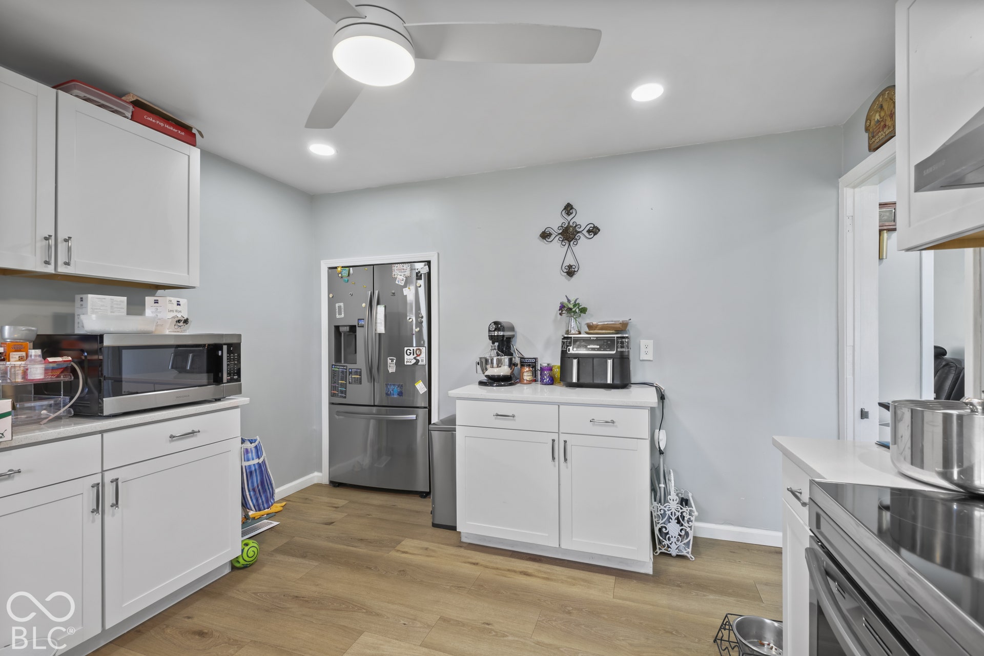Modern kitchen featuring white cabinetry, light-colored countertops, wood-finish flooring, recessed lighting, and a ceiling fan