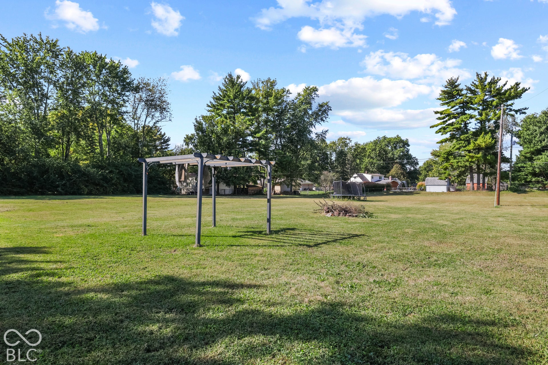 Expansive grassy yard area with a metal pergola structure