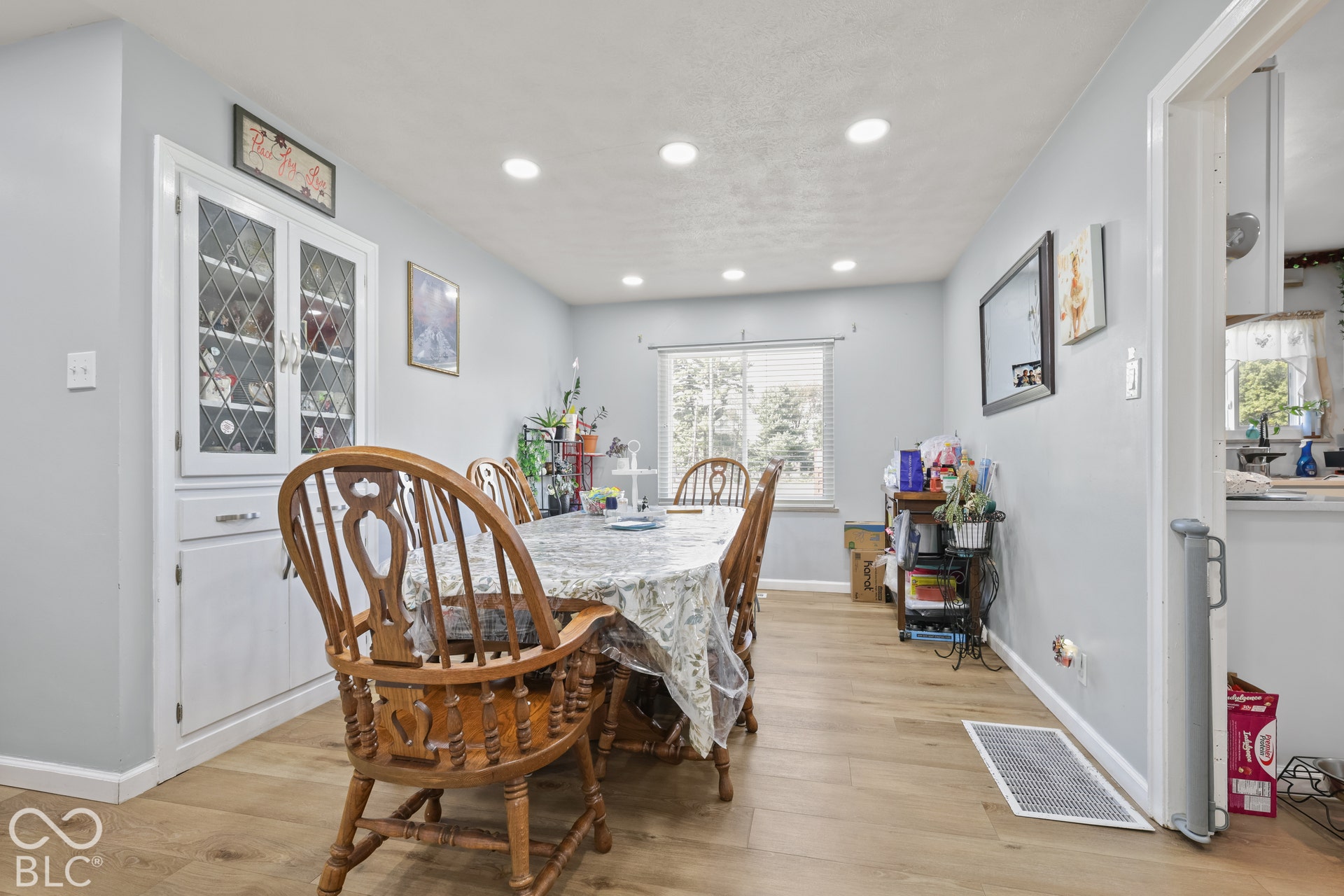 Recessed ceiling lighting, wood-finish flooring, built-in display cabinetry with glass paneling, window with horizontal blinds