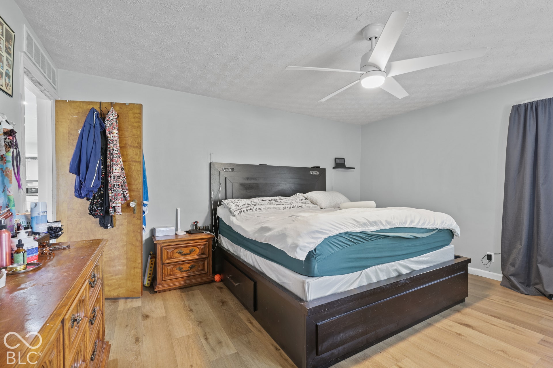 Wood-finish flooring throughout, light-colored walls, and a modern ceiling fan with integrated lighting