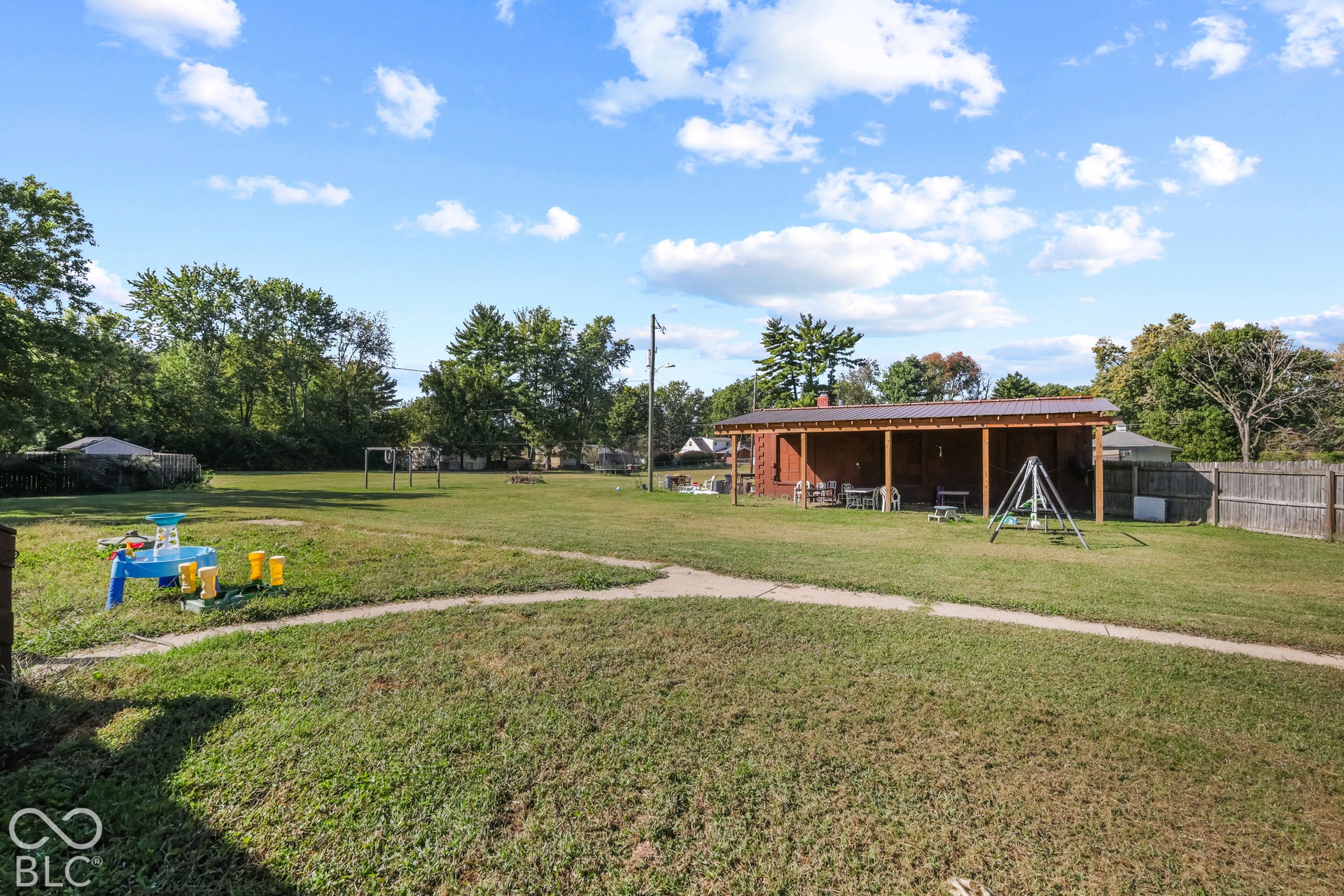 Expansive grassy yard with a concrete pathway and mature trees