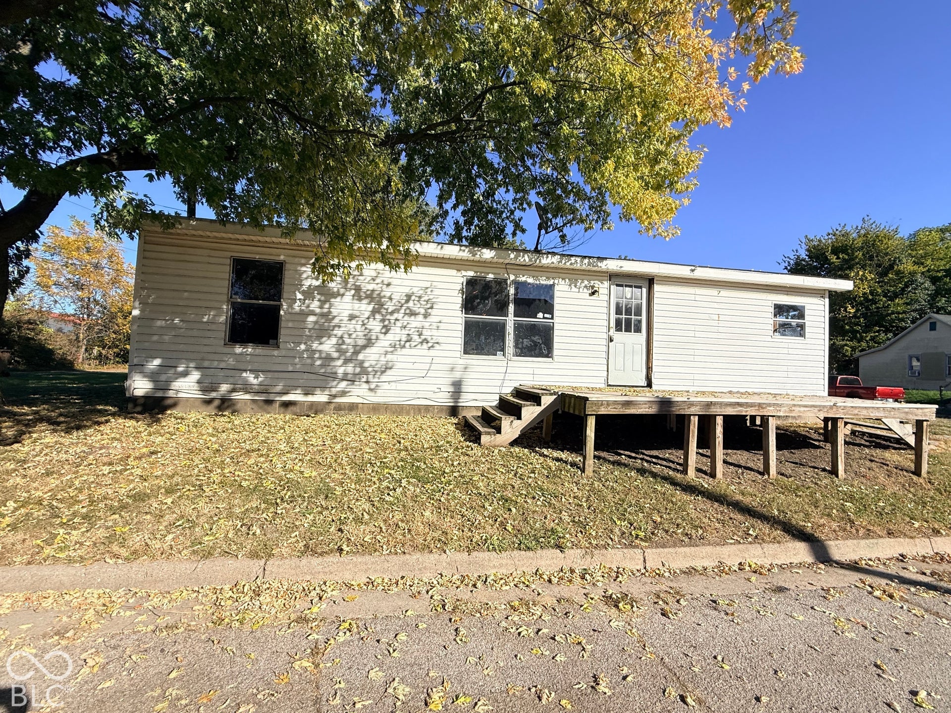 Exterior featuring white siding, a raised wood-finish deck with steps, and multiple windows
