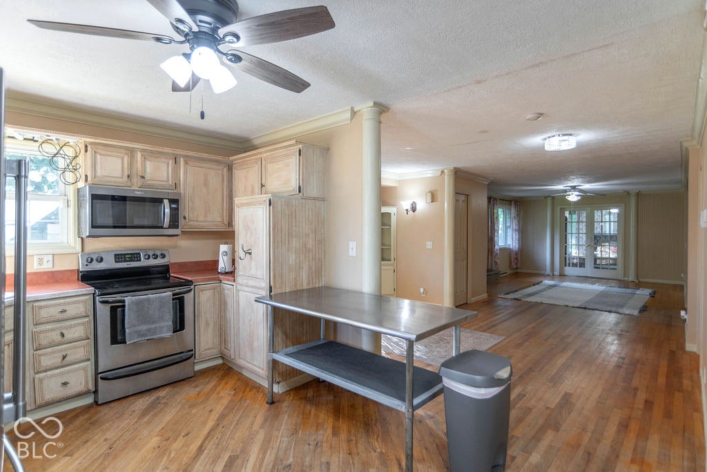 Kitchen featuring stainless steel appliances, wood-finish flooring, and white cabinetry