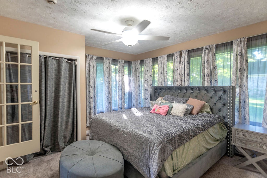 Ceiling fan, multiple windows, built-in closet with curtain, and carpeted flooring