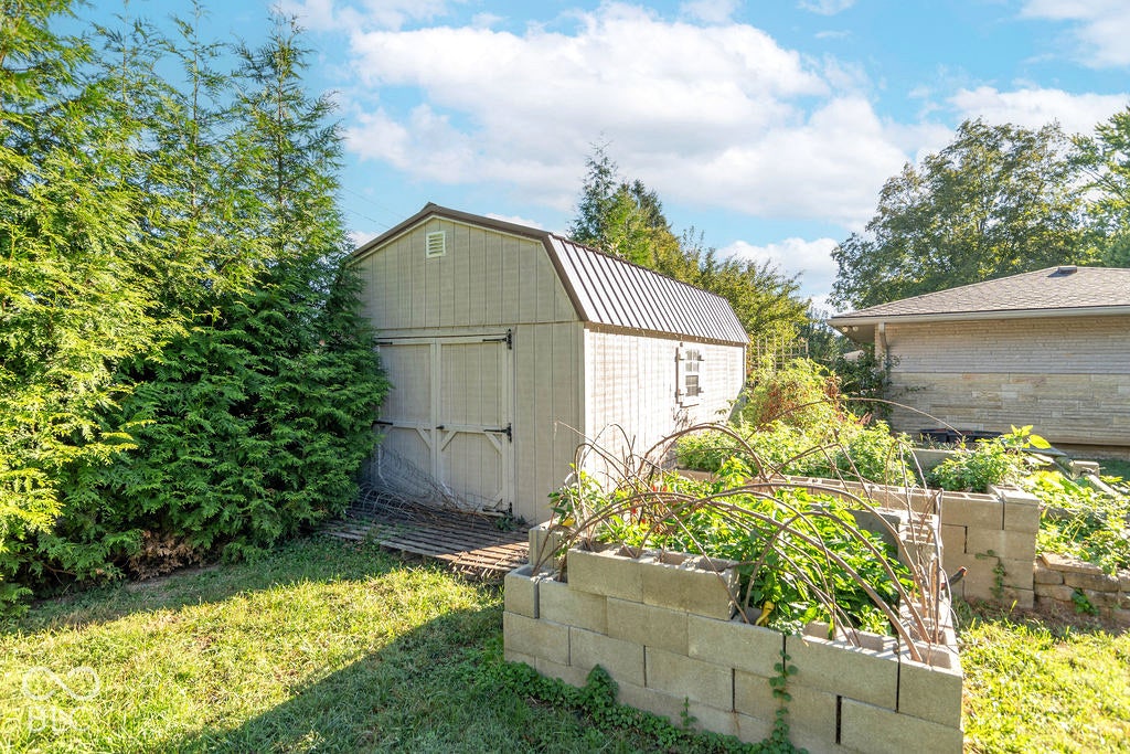 Gable-roof storage shed with a metal roof, double entry doors, and a side window