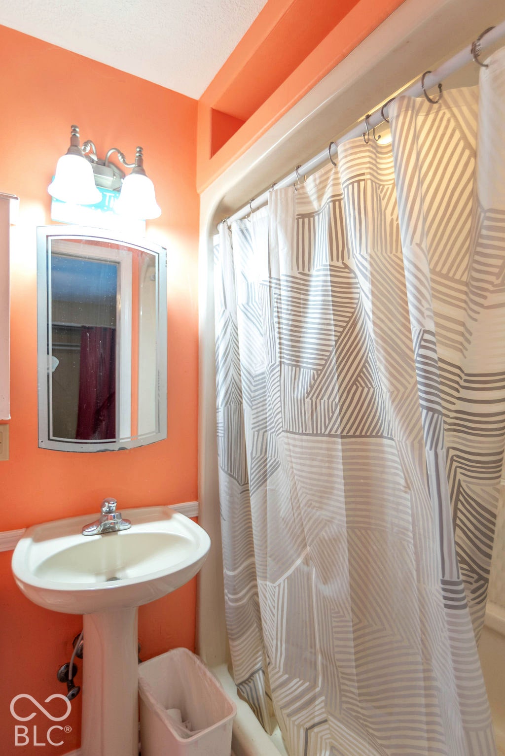 Pedestal sink, wall-mounted light fixture, and mirrored medicine cabinet